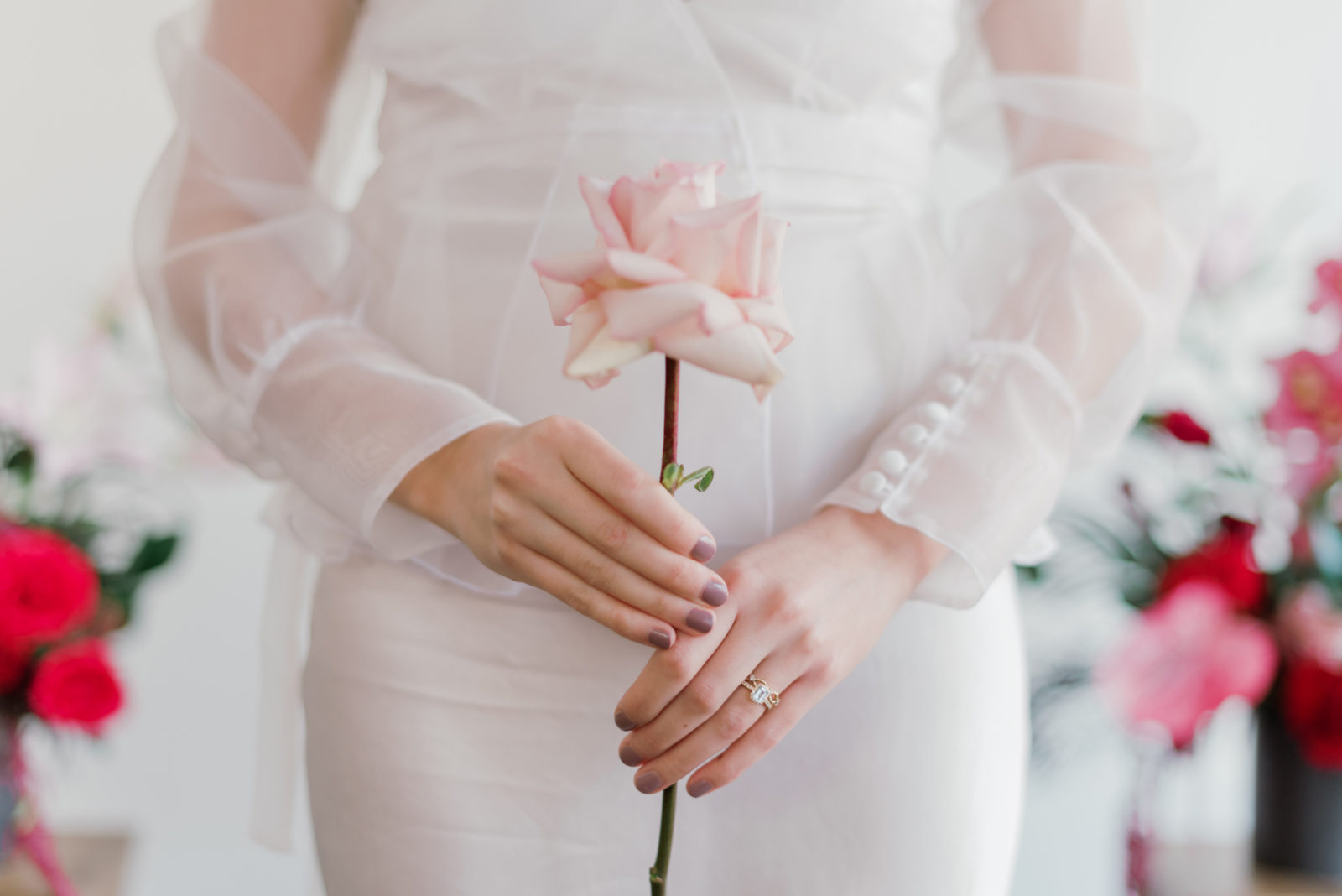 Bride poses with a pink garden rose for this modern microwedding inspiration