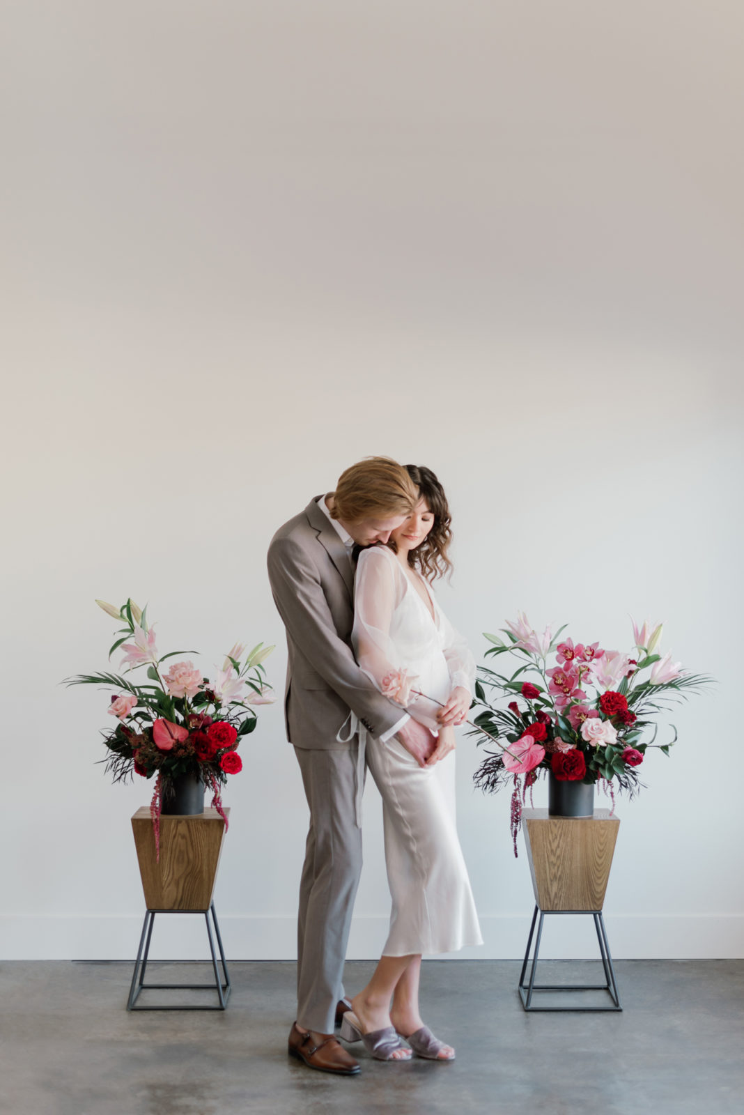 Modern wedding inspiration with a short bridal dress, a grey suit, and vibrant pink and berry hued florals