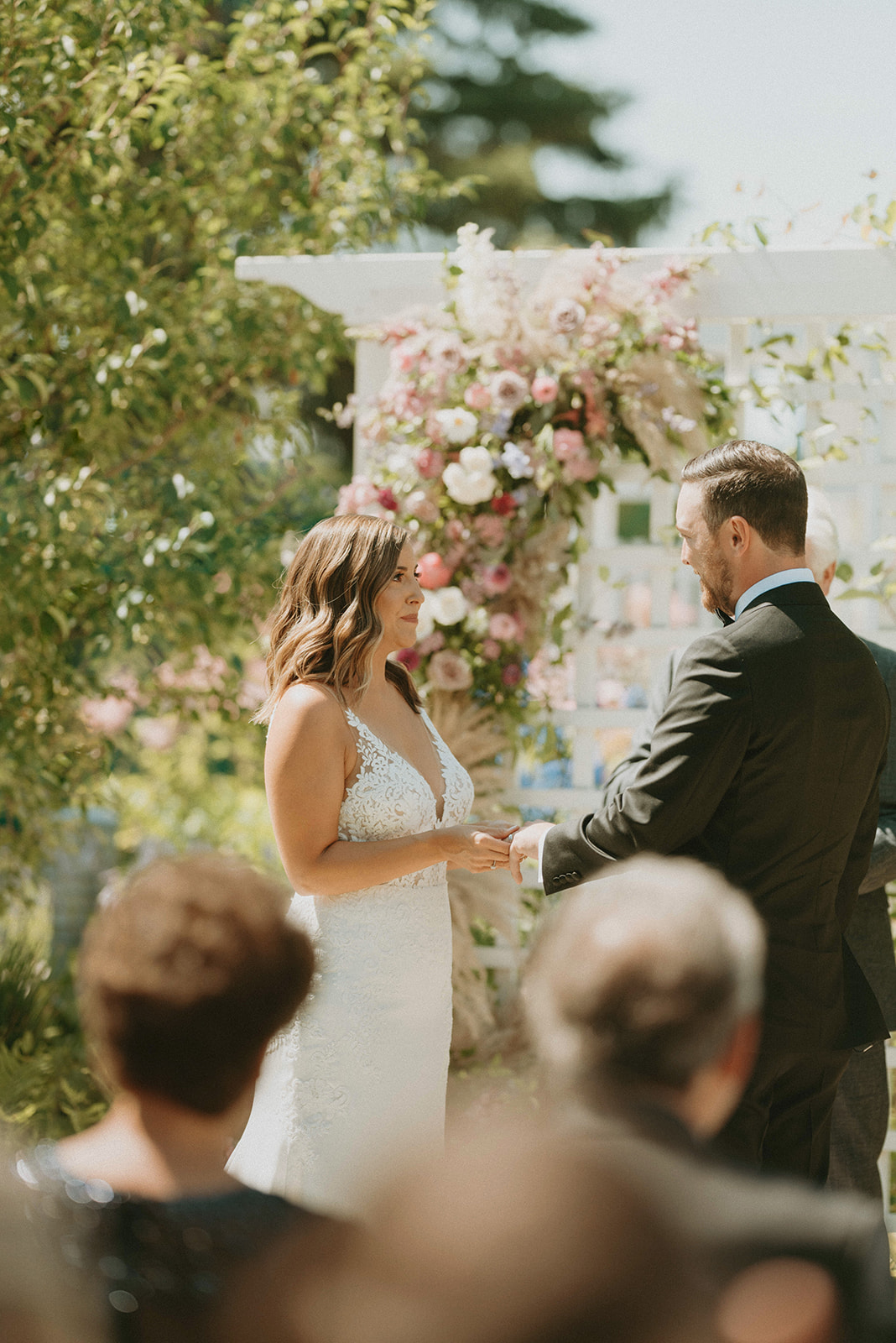 Outdoor summer wedding ceremony at the Deane House with bride and groom sharing their vows in front of a floral arch