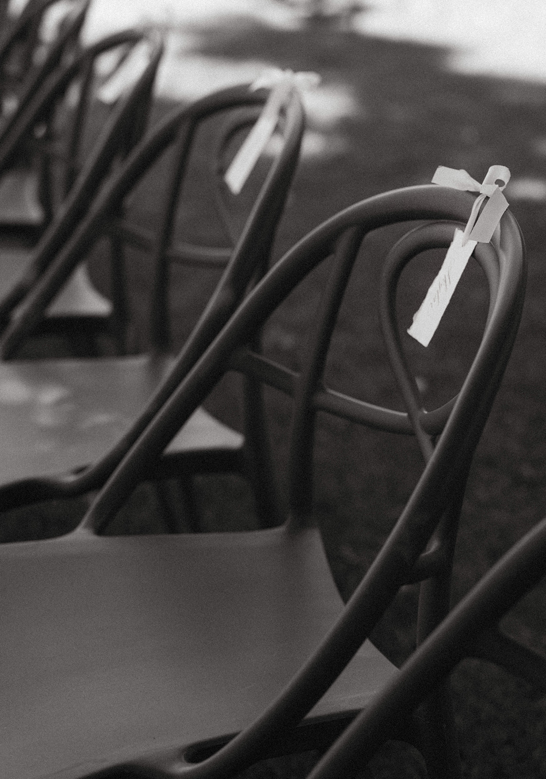 Black and white photo of wedding ceremony chairs with white ribbon name tags