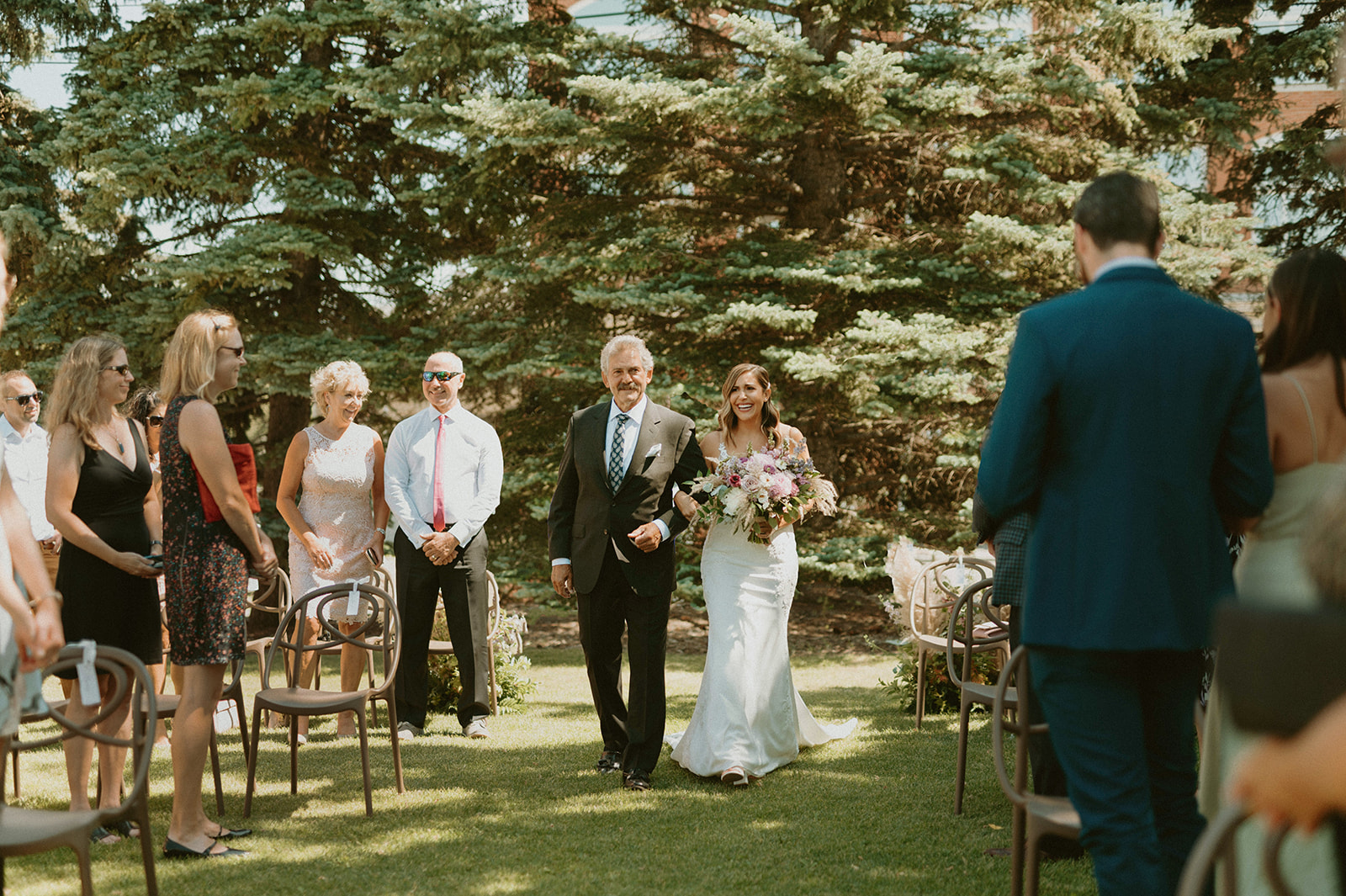 Father and bride walk down the aisle at this outdoor wedding ceremony at Deane House