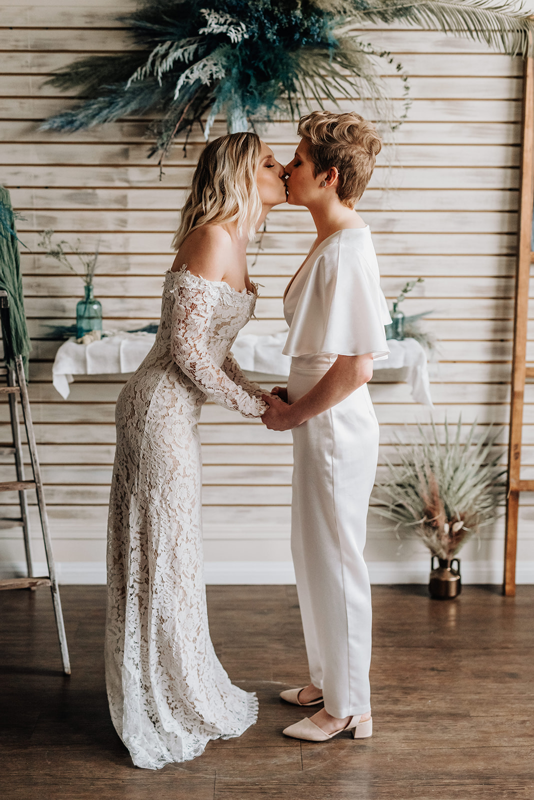 Brides share a kiss in front of their blue and bohemian ceremony decor for this mini elopement