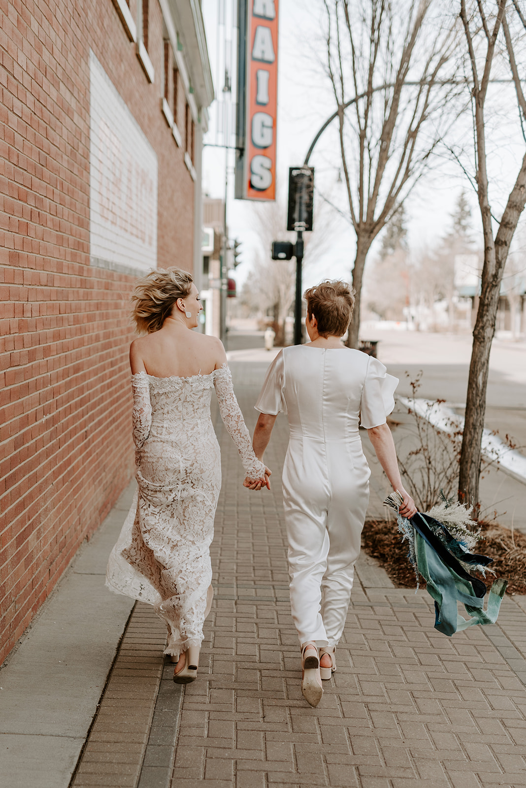 Chic bridal attire featuring a lace off the shoulder gown and bold white jumpsuit