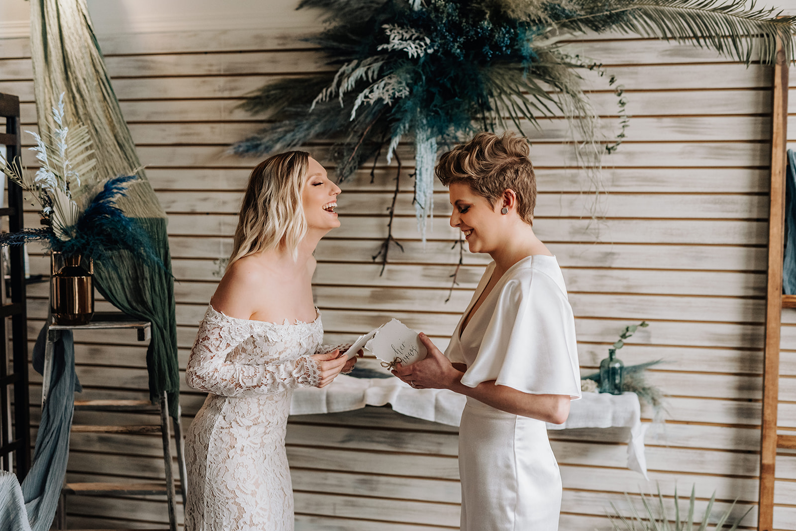 Brides share a laugh as they exchange wedding vows for their blue bohemian wedding ceremony