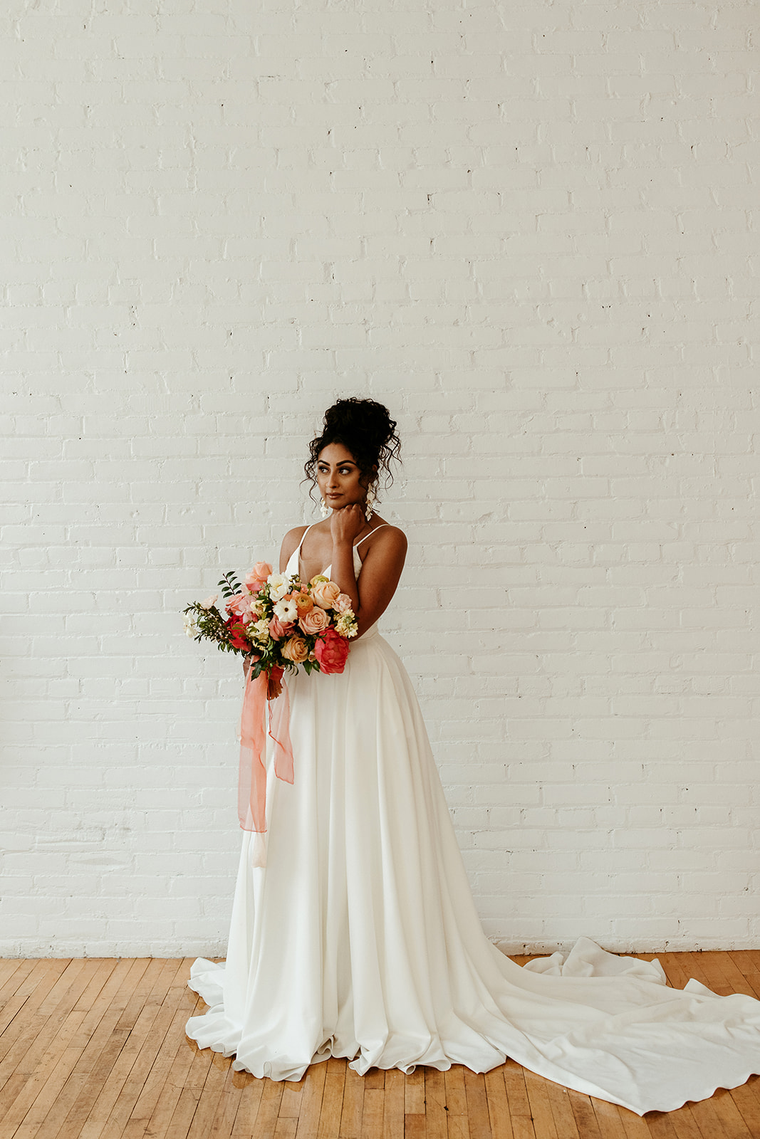 Bold boho bridal updo for the bride with curly hair featuring a colour palette with bold citrus hues