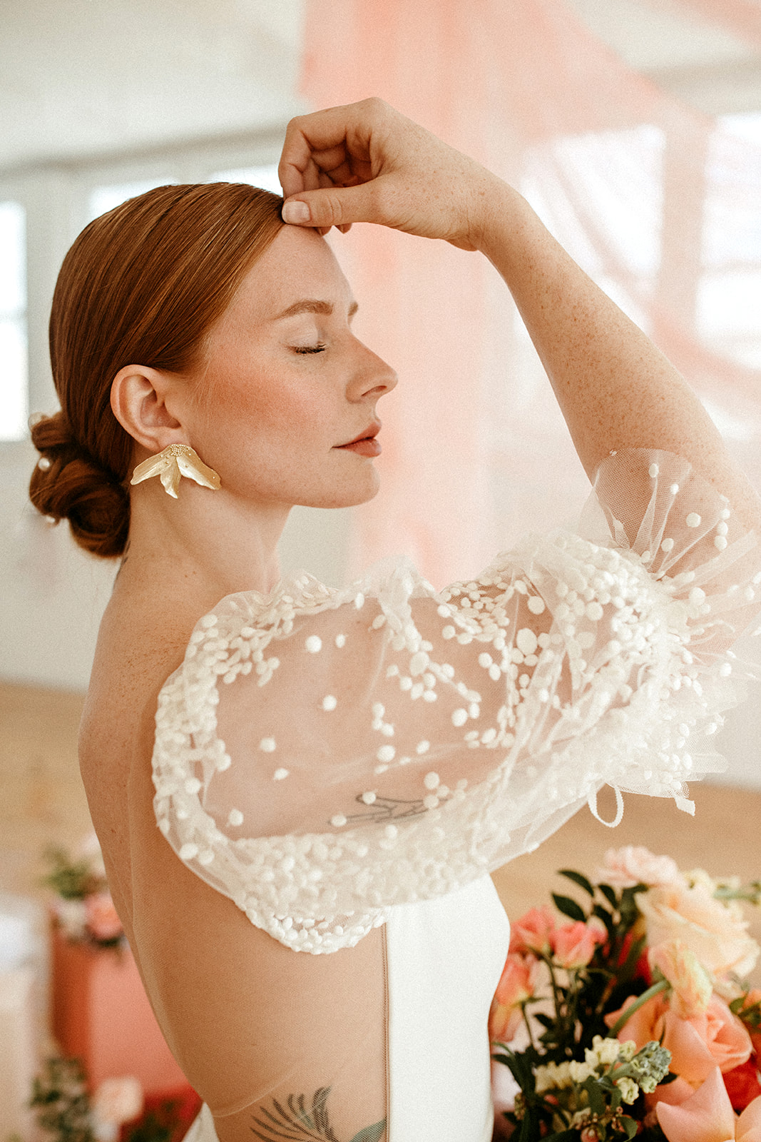 Sleek bridal updo, bold boho earrings and a puff sleeved gown with floral details
