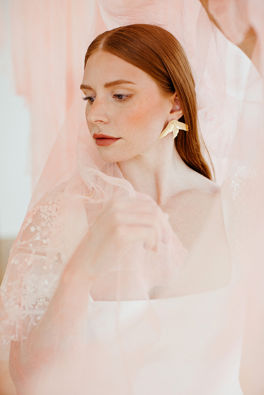 Red head bridal portrait with light pink fabric as a backdrop