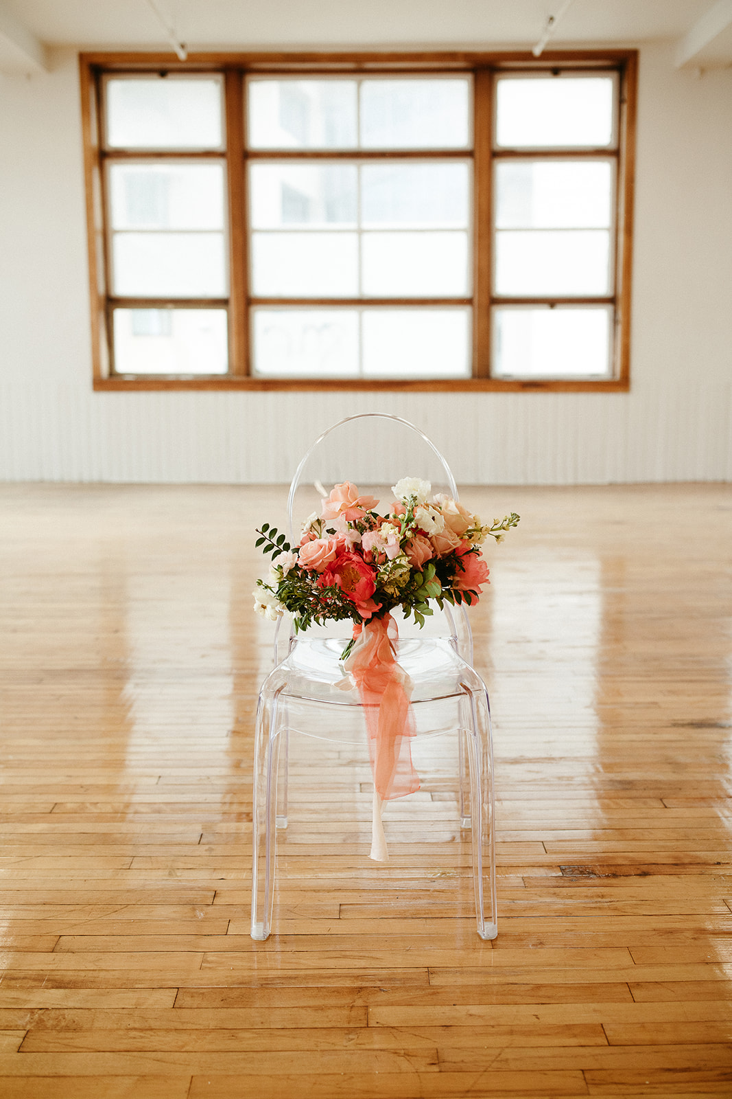 Clear wedding ceremony chair from Special Event Rentals with a bold citrus bridal bouquet design by Therese Lopez Florals