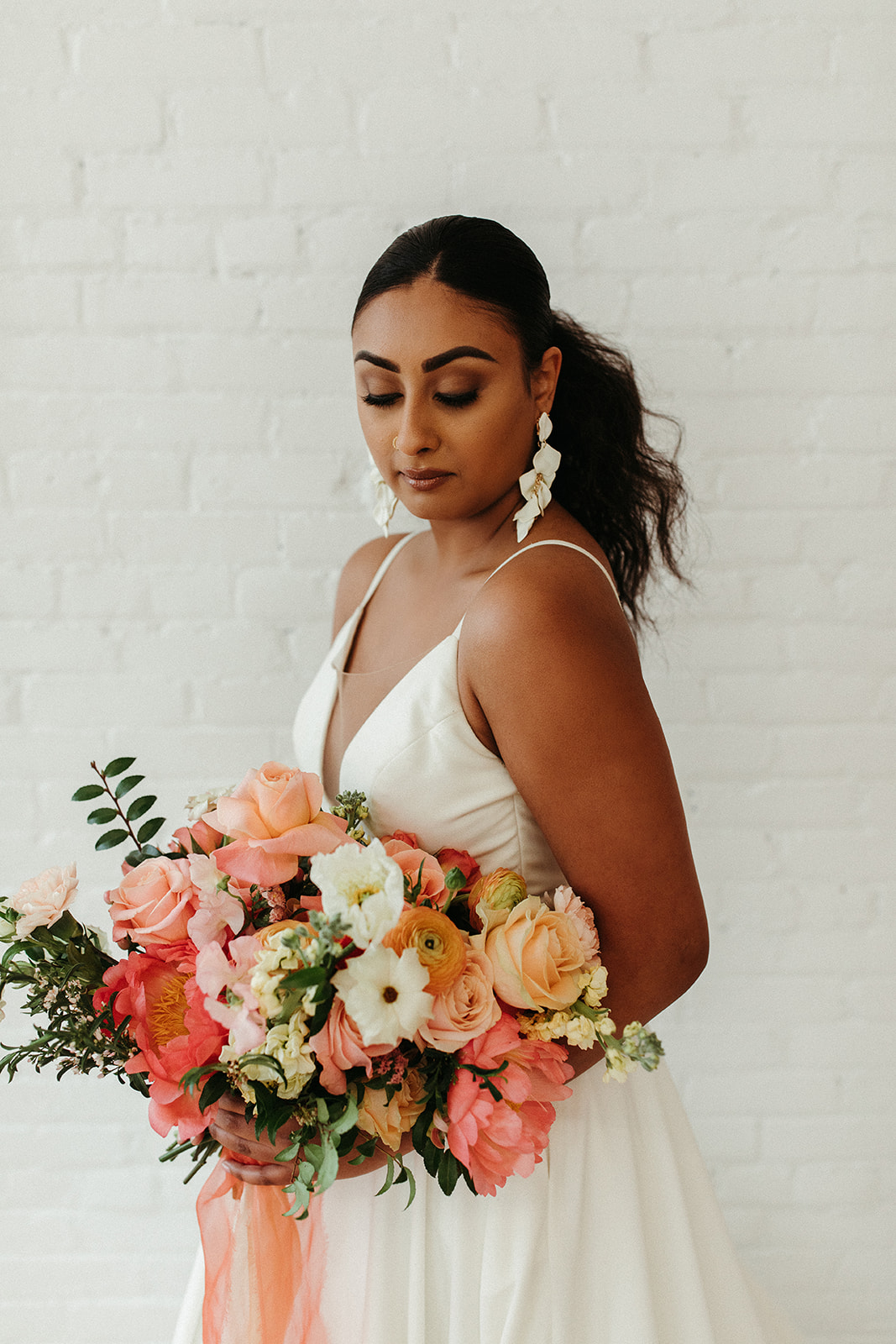 Sleek hair styling for the boho bride with bold citrus floral bouquet