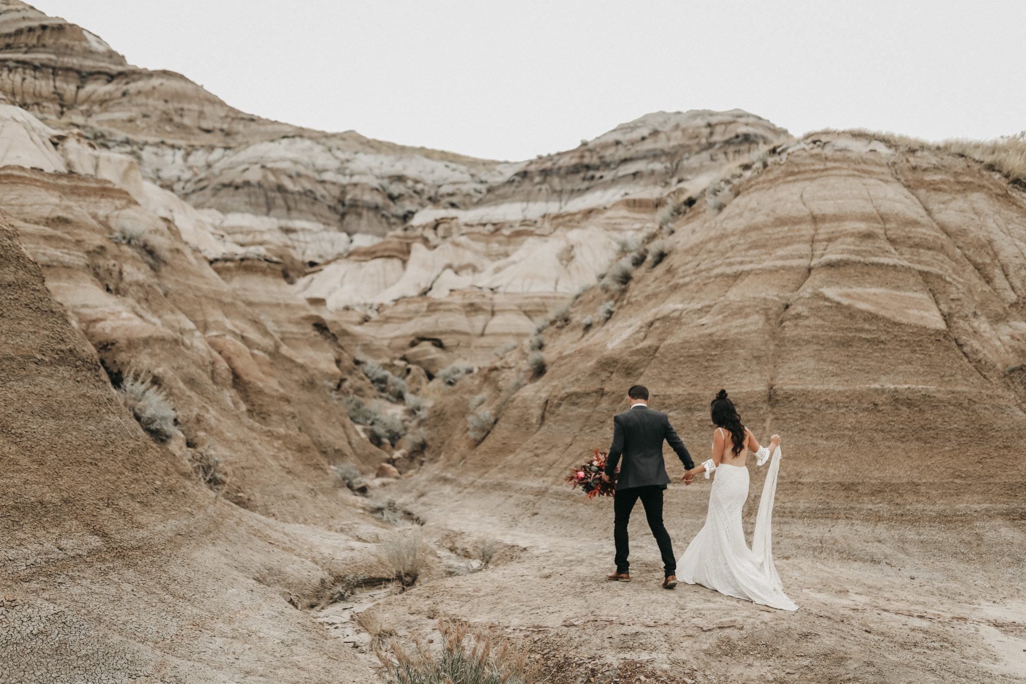Bride and groom walk through the sand hills in Drumheller Alberta 