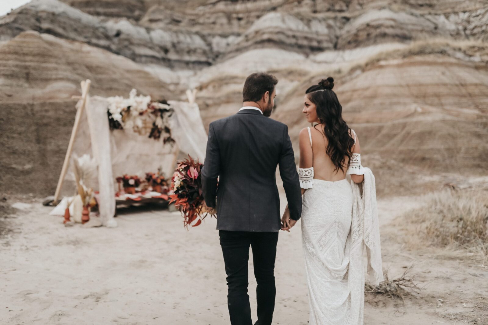 Bride and groom walk towards a boho decorated tent for this Moroccan elopement inspiration
