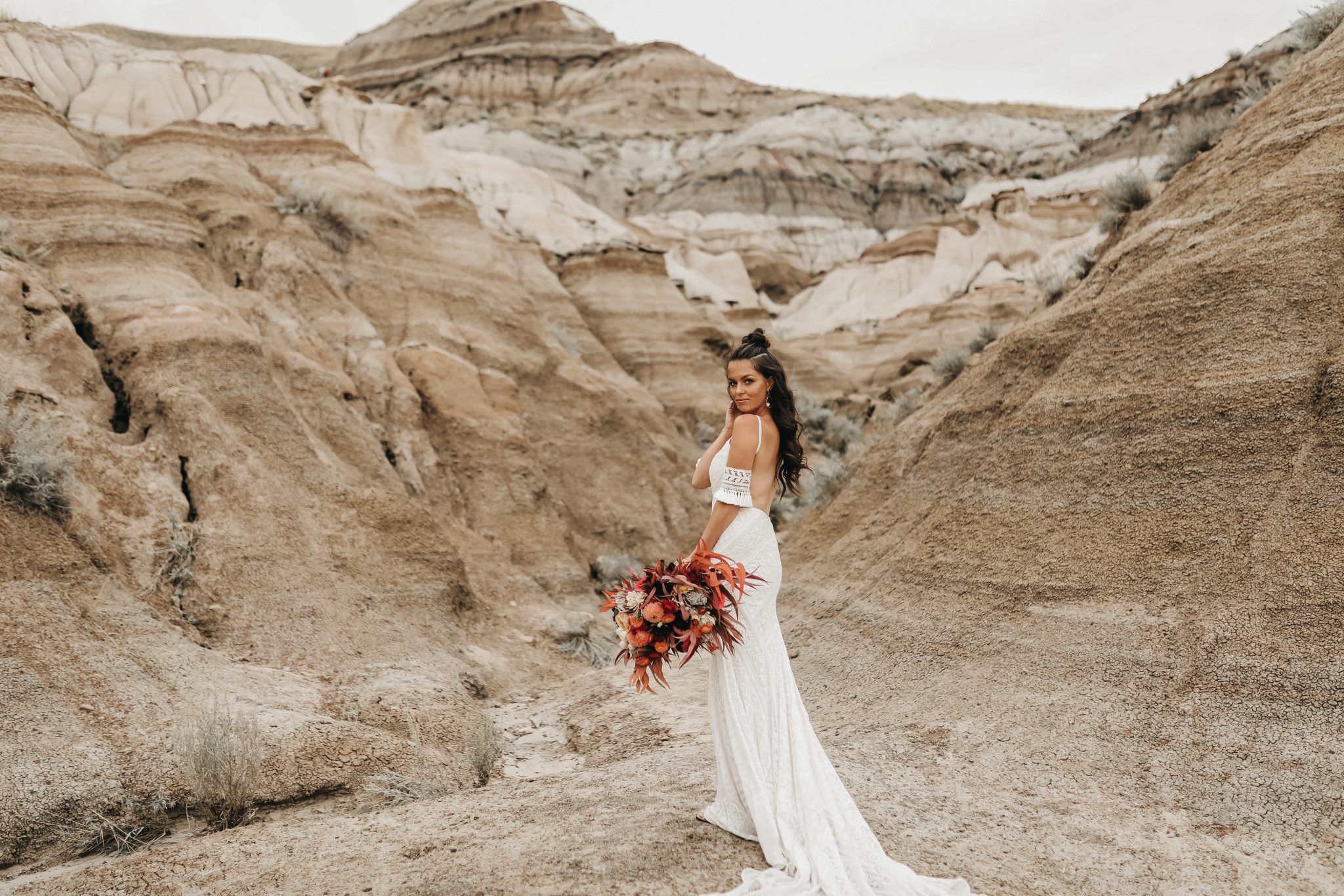 Bride poses in a lace dress against the sand hills of Drumheller for this Moroccan inspired elopement