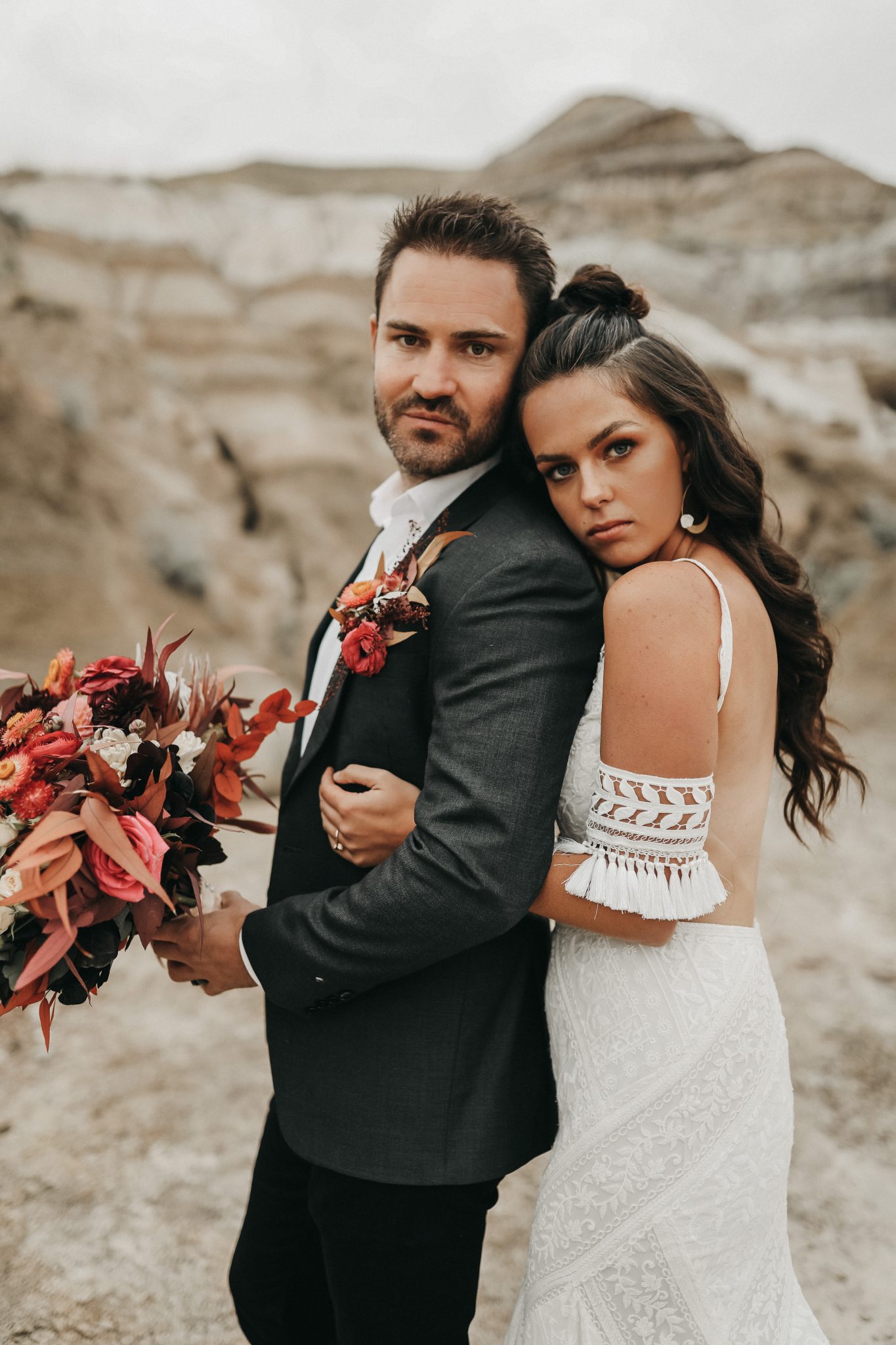 Bride and groom pose in Moroccan Elopement Inspiration attire featuring lace bridal cuffs and a grey suit