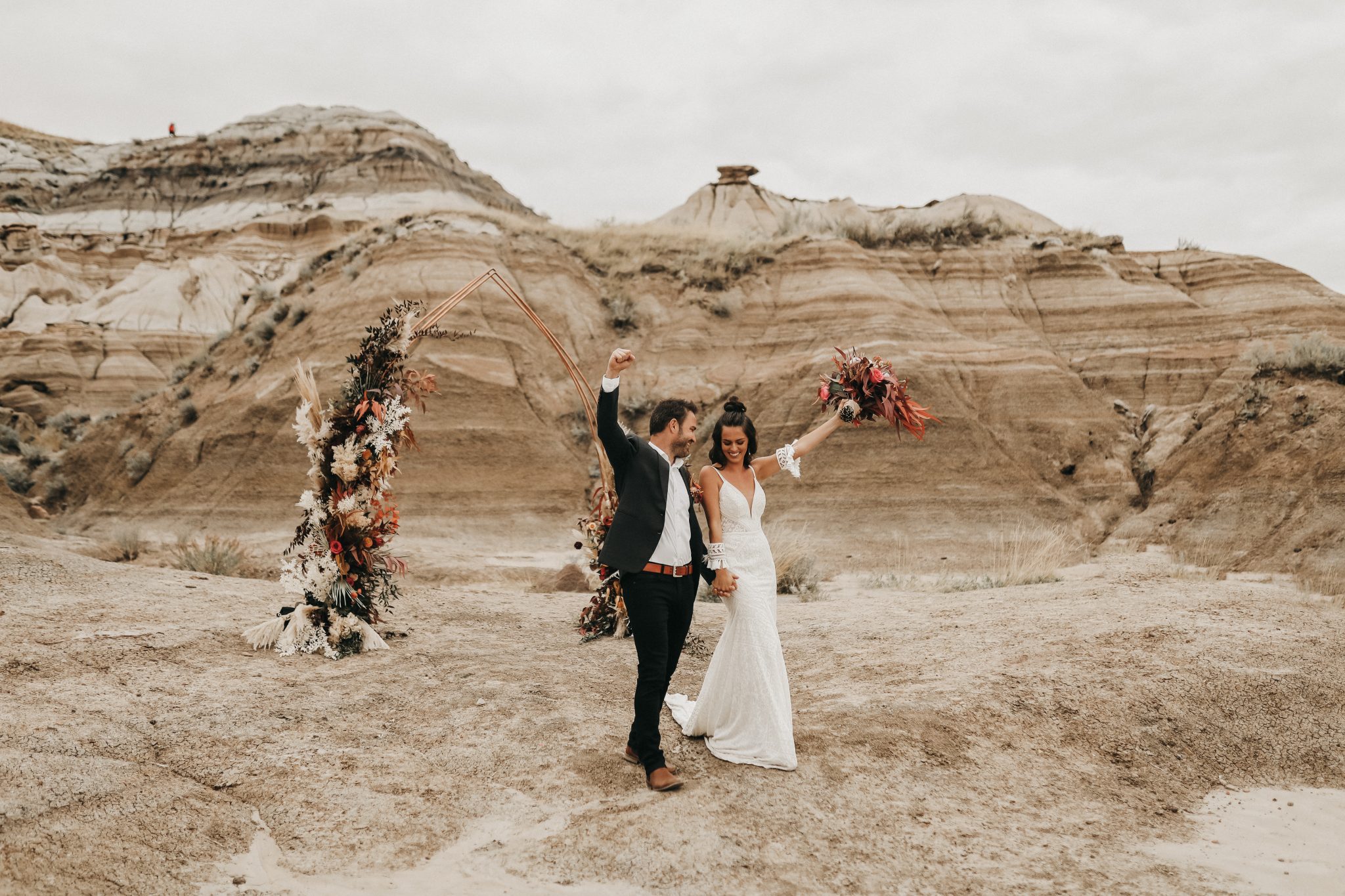 Bride and groom pose in front of a copper arch with boho florals for a moroccan inspired elopement in Drumheller Alberta