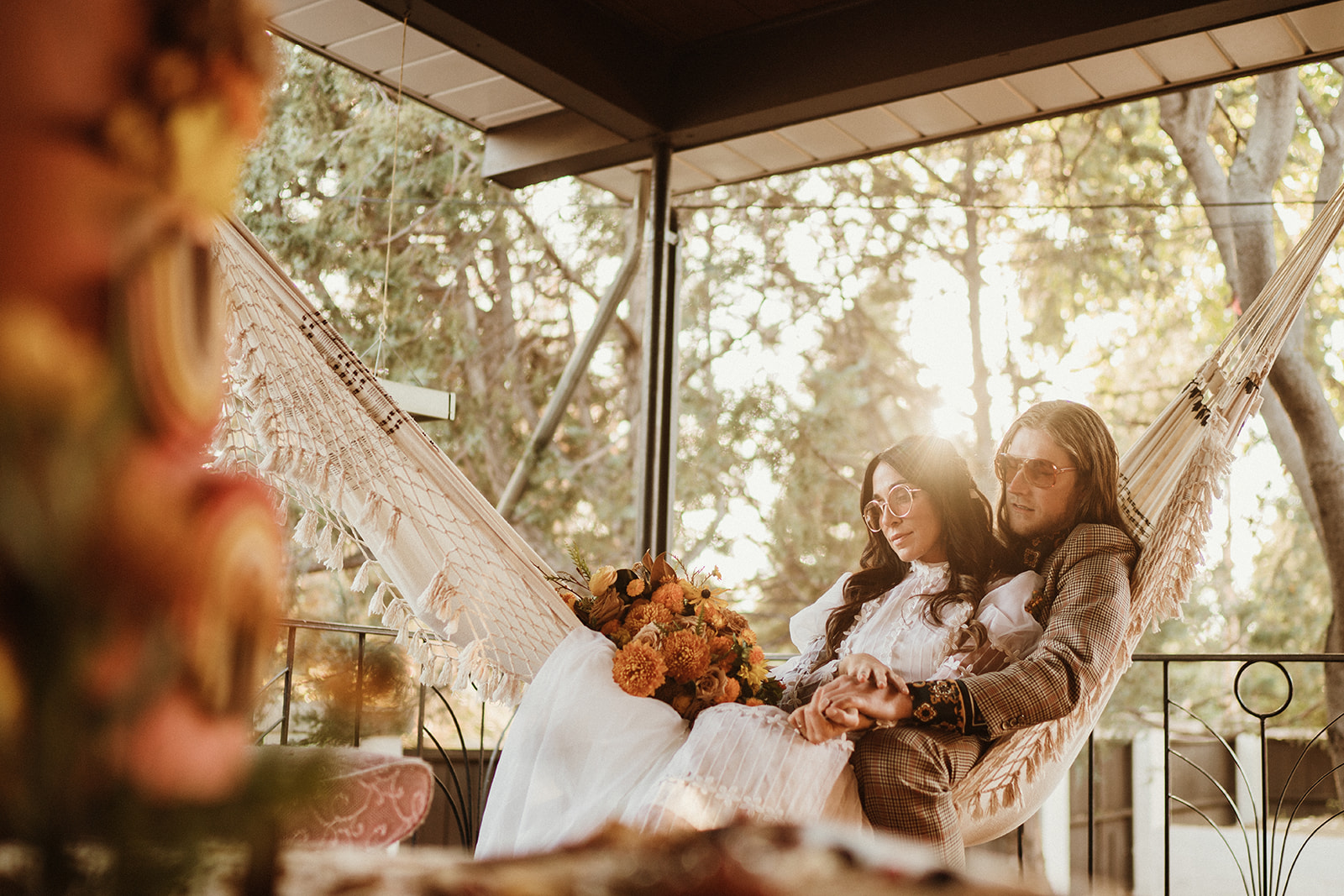 70's inspired retro wedding couple swing on a macrame hammock in a screened in porch on their wedding day for a 70's Backyard Wedding Inspiration