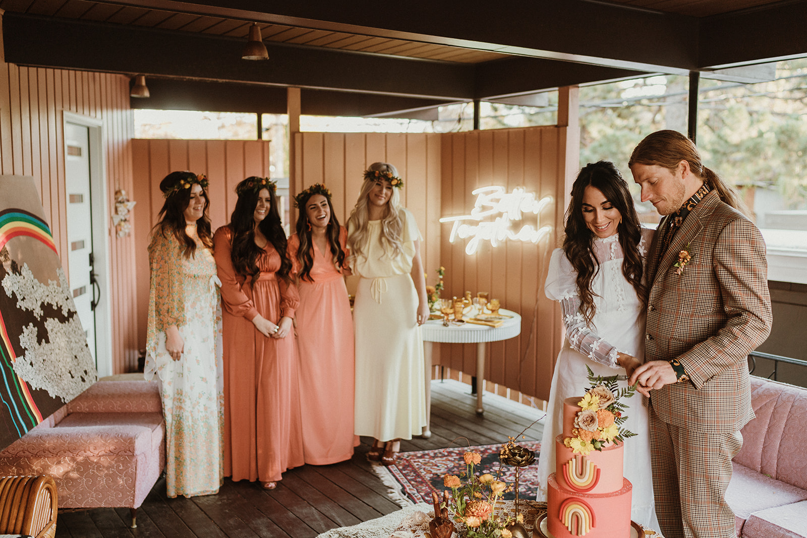 Casual and retro inspired bride and groom cut into their bohemian wedding cake with a blush and tangerine retro inspired colour palette 