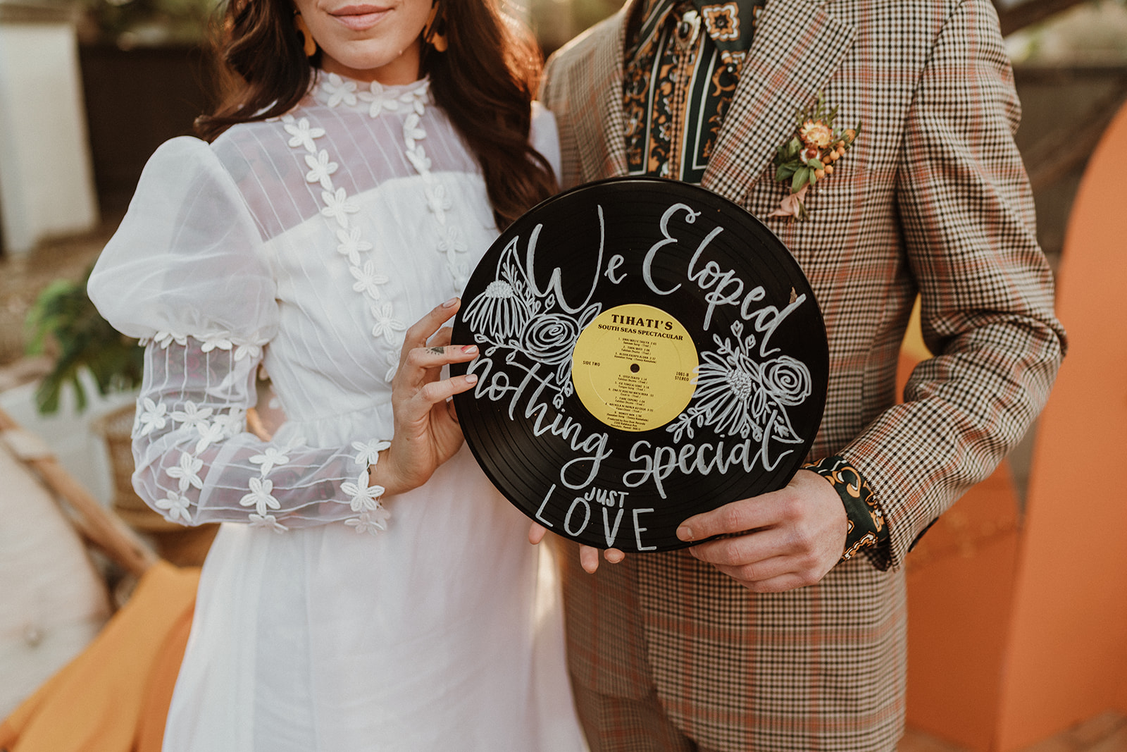 Bride and groom hold a record with the words We Eloped written on it