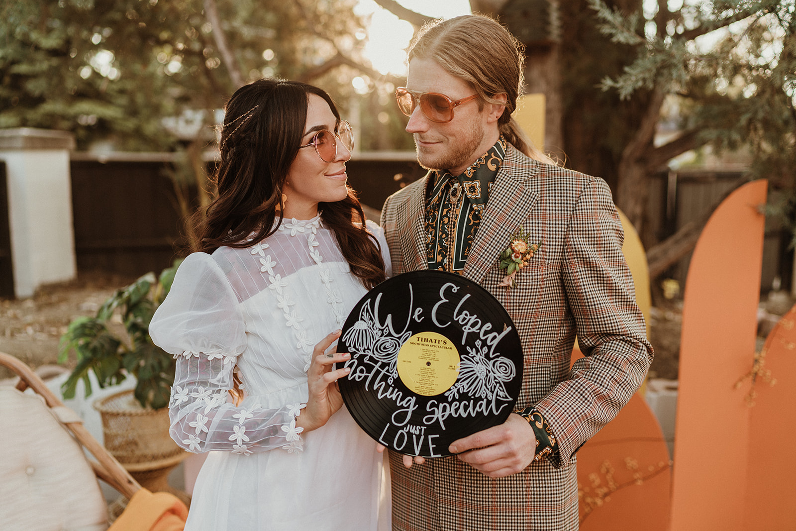 Retro bride and groom hold a creative We Eloped sign, created from a record