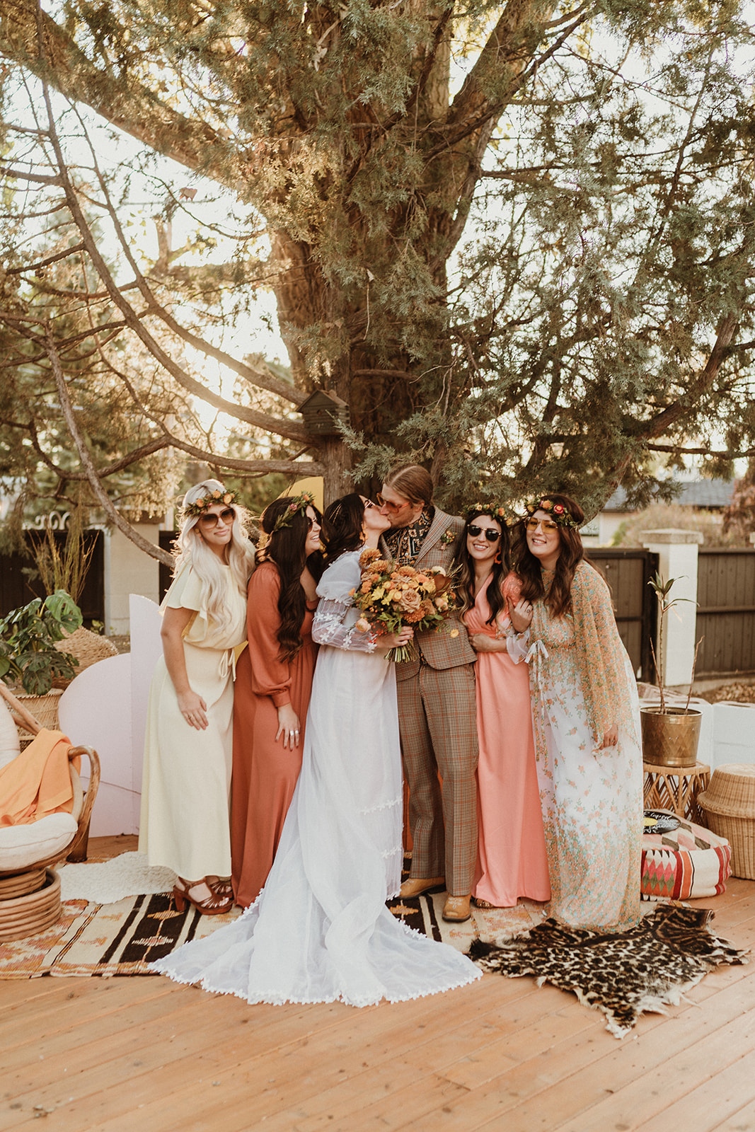 Groovy retro bride and groom share a kiss under a tree on their wedding day for 70's Backyard Wedding Inspiration