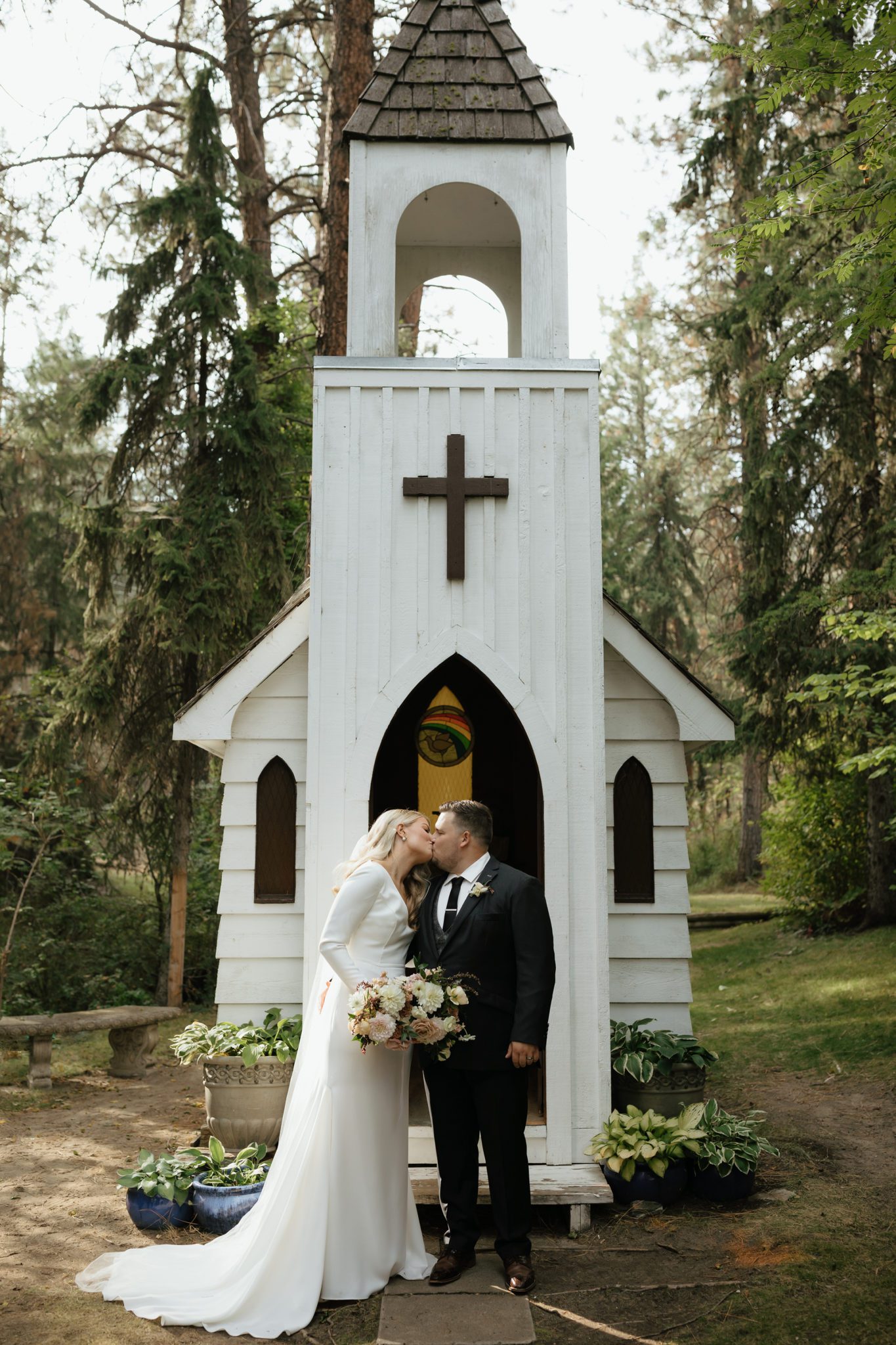 Bride and groom share a kiss in front of the tiny white chapel in Okanagan British Columbia, the heart of wine country