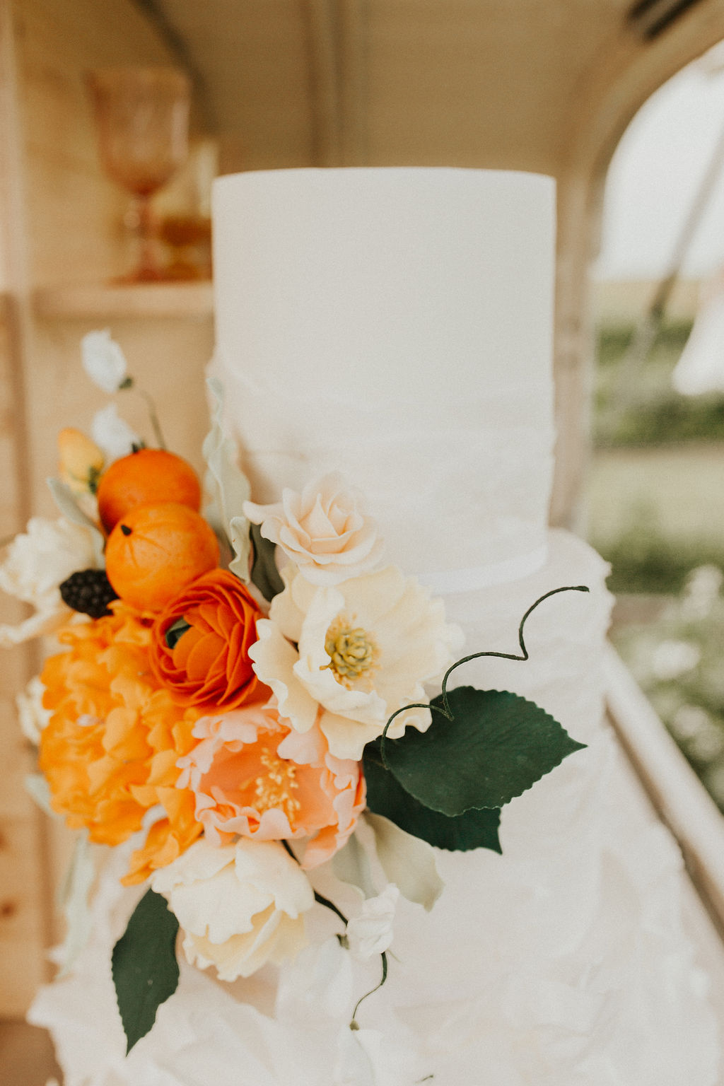 Stunning ruffled white wedding cake with bright tangerine inspired floral accents