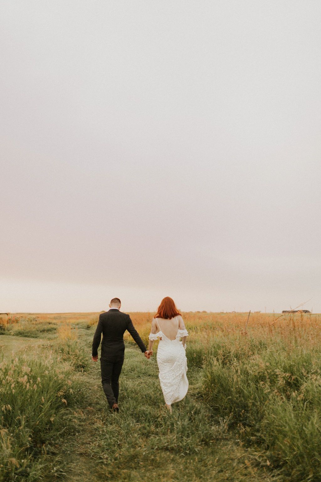 Bride and groom walk through a farmers field at sunset
