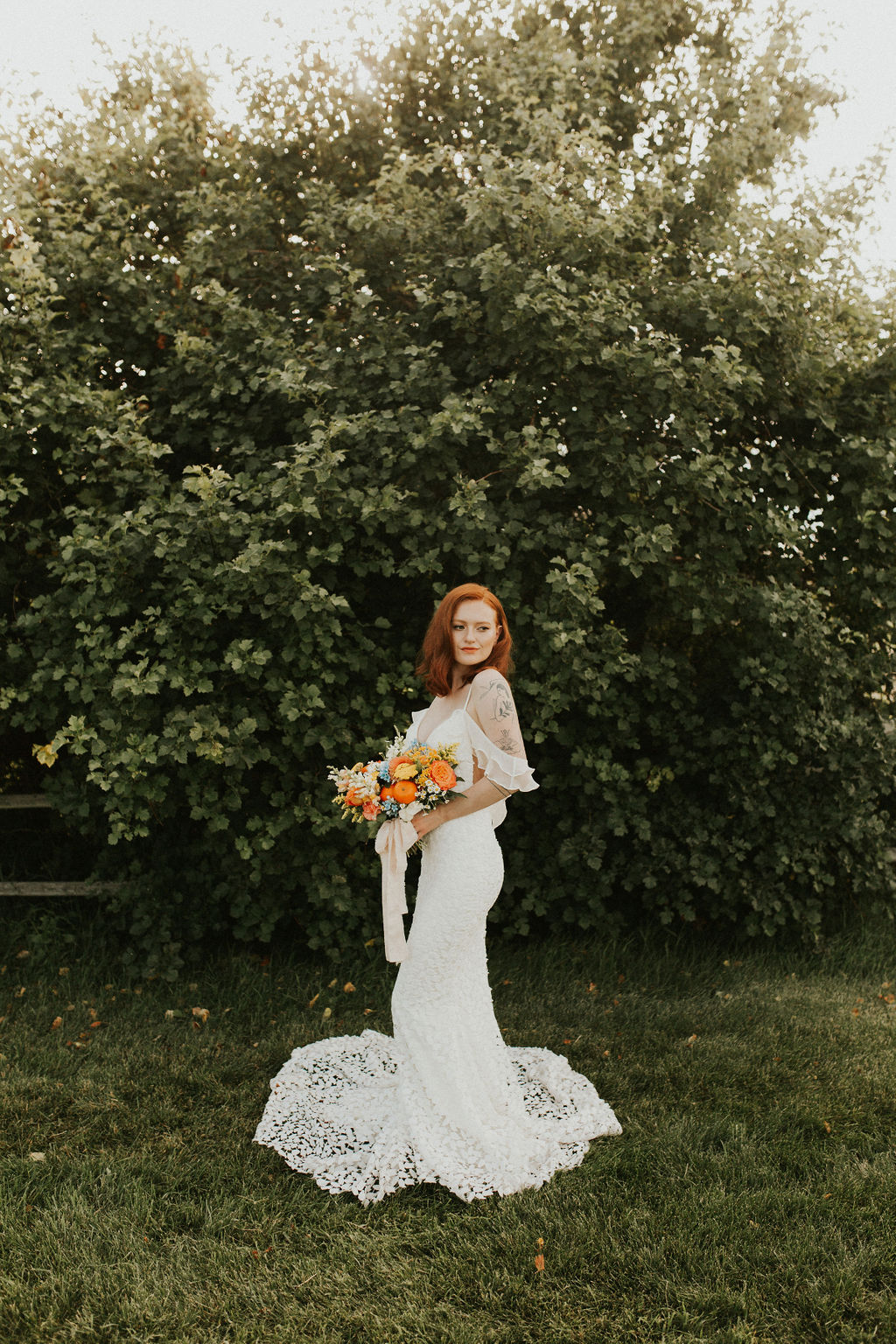 Bride poses in a stunning off the shoulder ruffle gown with a bold summer bridal bouquet