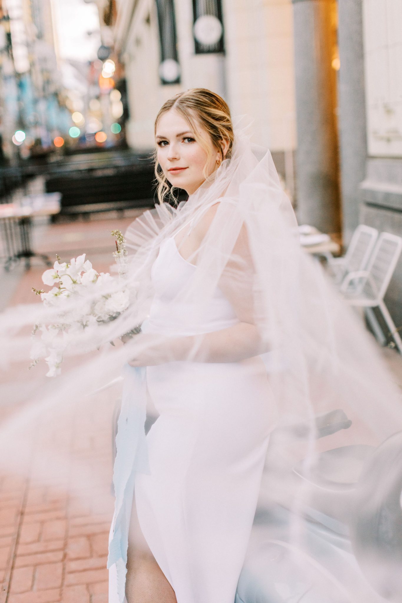 Modern downtown bride with flowing veil outside of the Hudson in Calgary