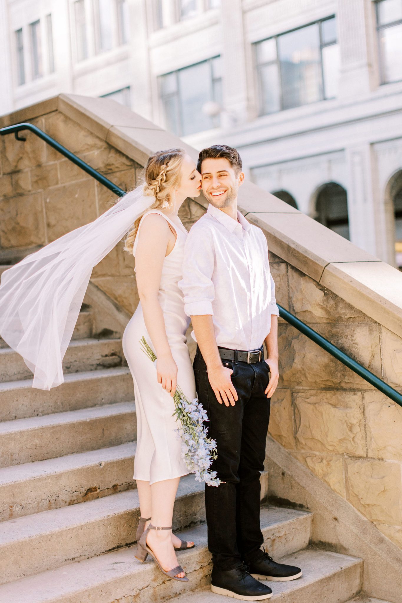 Bride and groom pose on city steps in the heart of downtown Calgary for this modern elopement shoot with hints of a European getaway