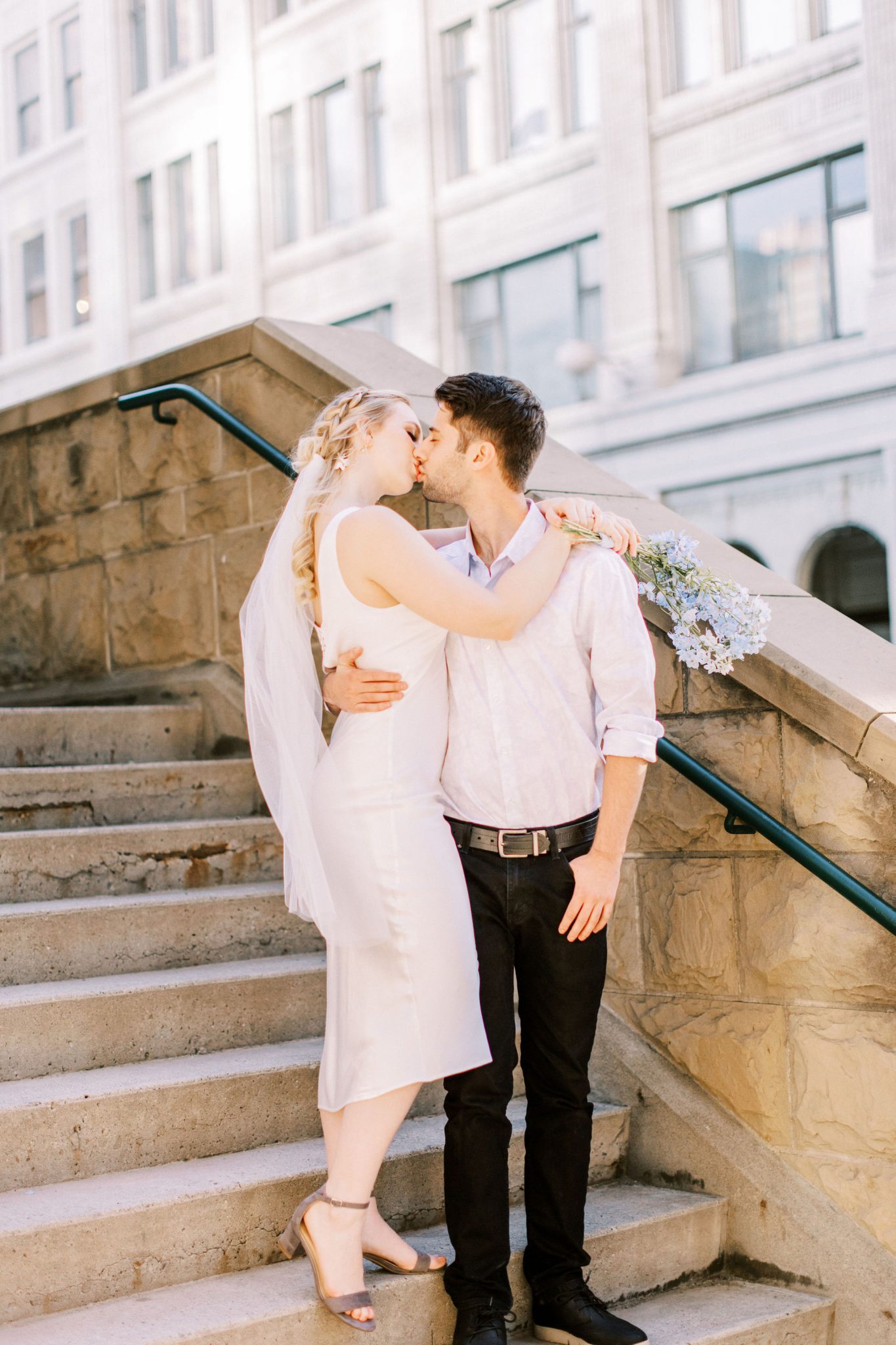 Bride and groom share a kiss on city steps for this downtown Calgary elopement with European inspiration