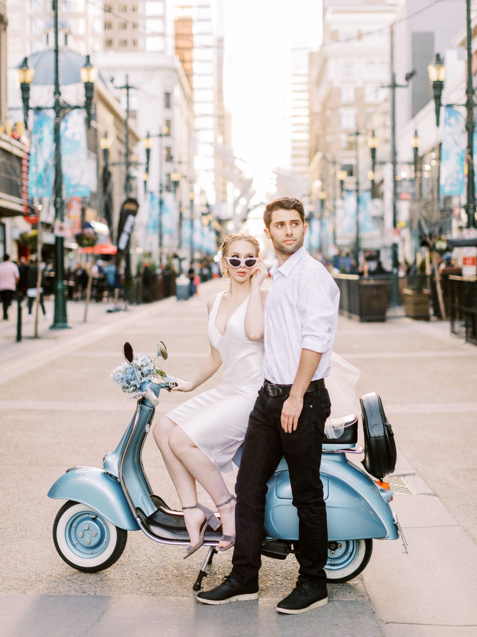 Modern bride and groom on Stephen Avenue in Calgary Alberta with a blue vespa
