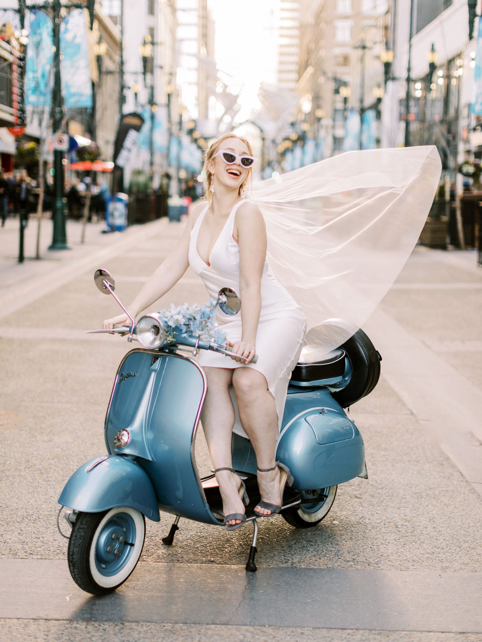 Modern bride with flowing veil on a blue vespa for this modern downtown elopement shoot