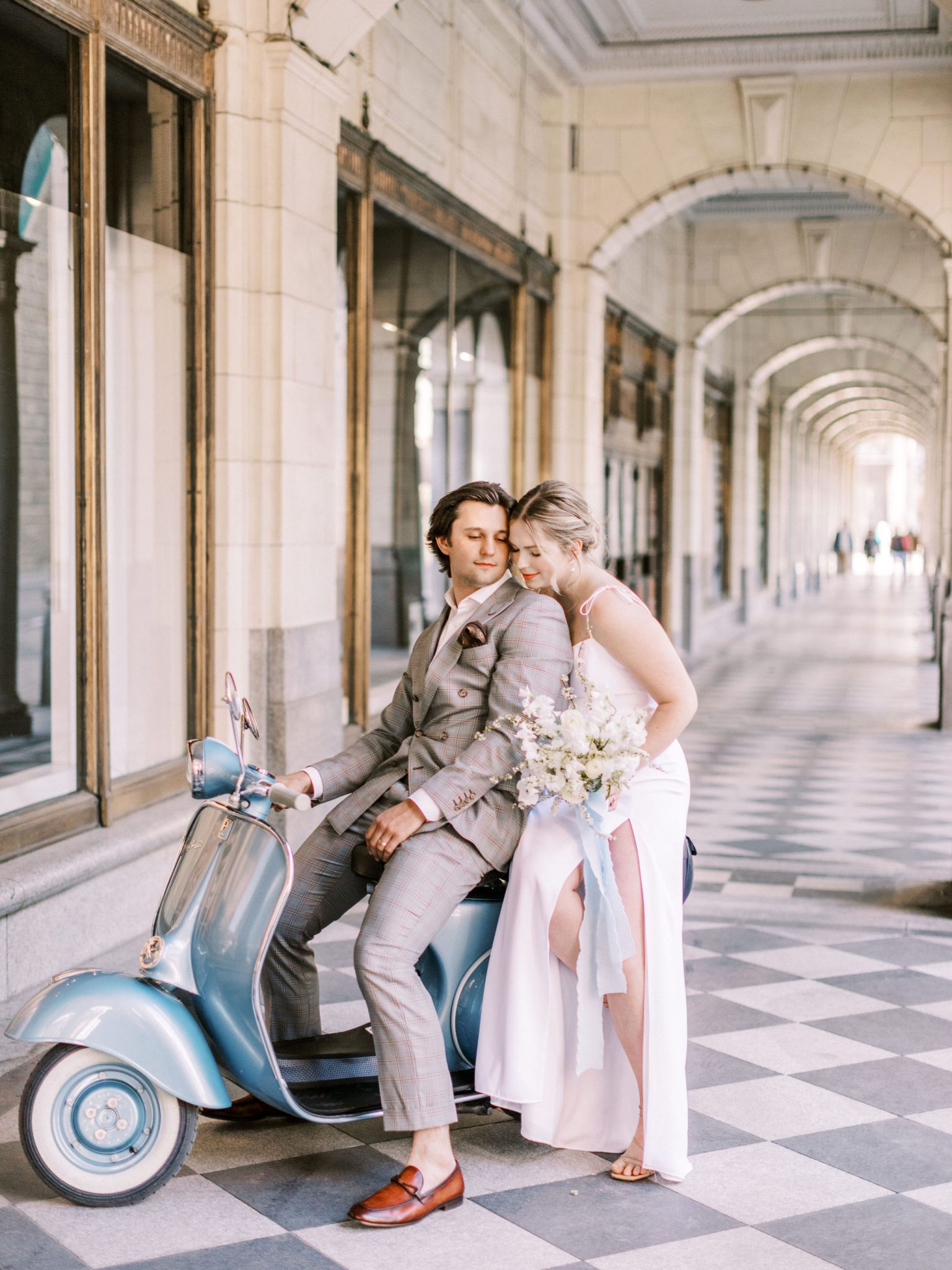 Modern downtown elopement with a white slip bridal gown, grey suit and blue rental vespa