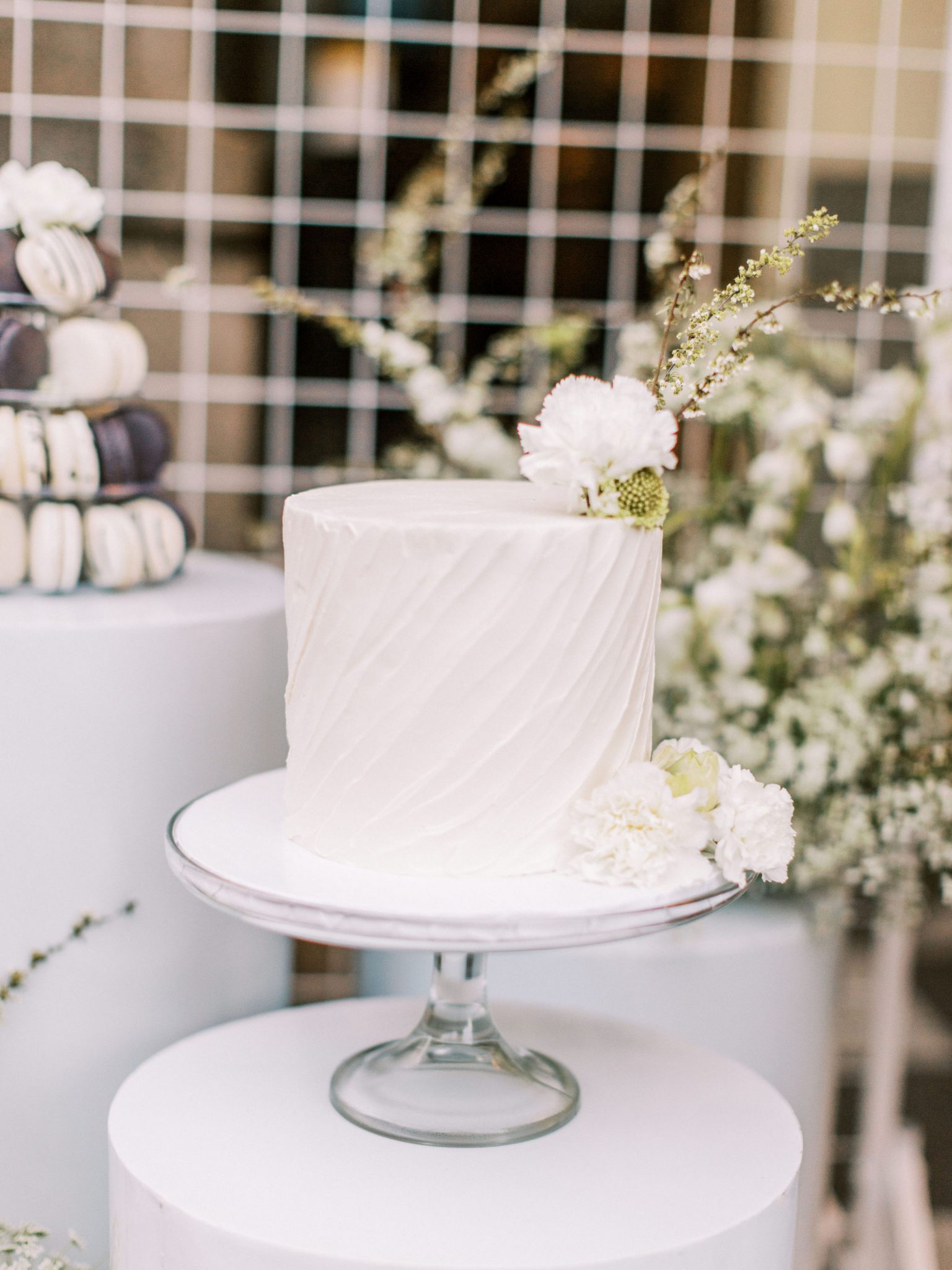 Modern white wedding cake with swirling icing and green flower accents