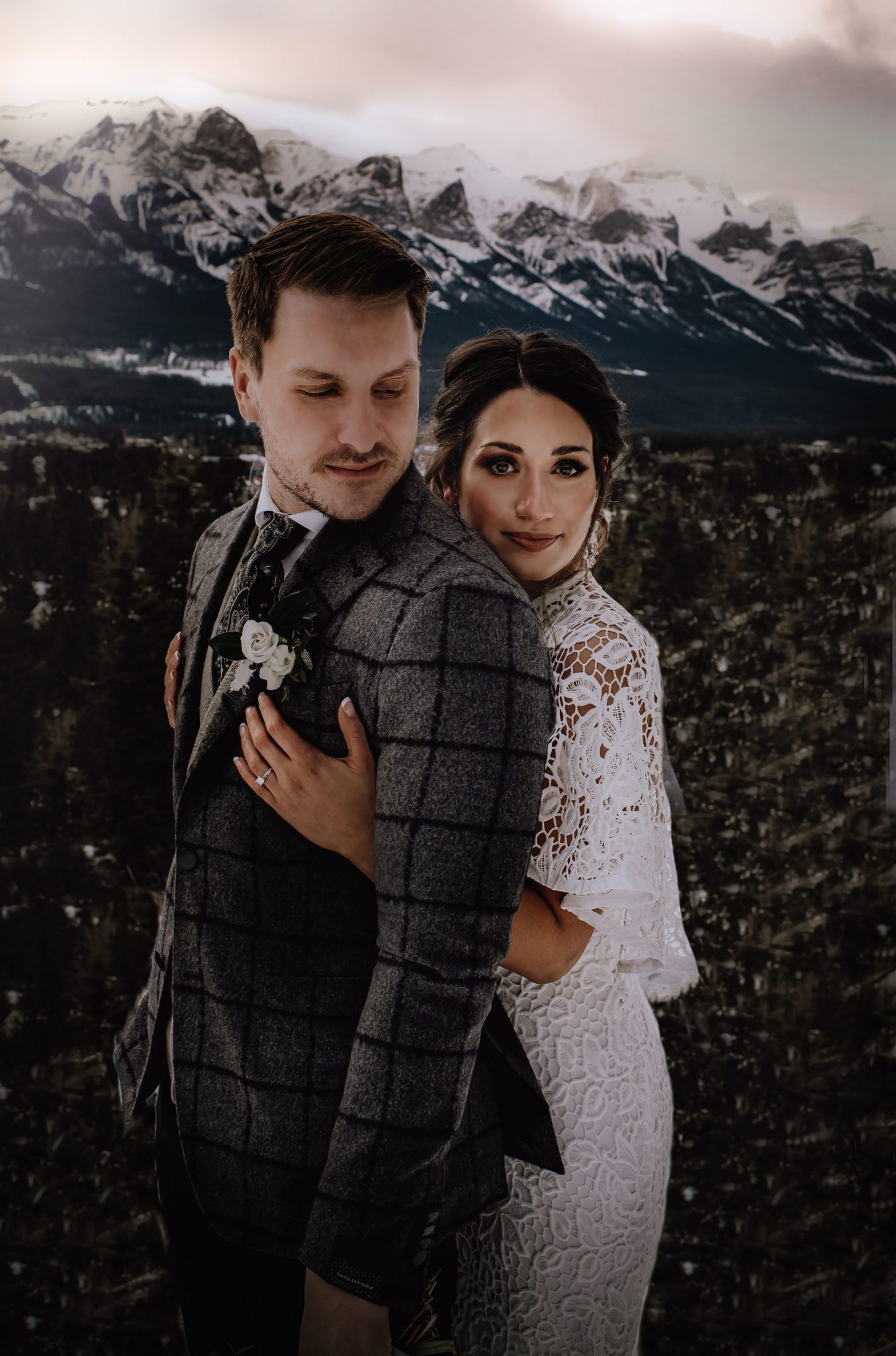 Bride and groom pose for a moody winter wedding portrait with the Canadian Rocky Mountains in the background 