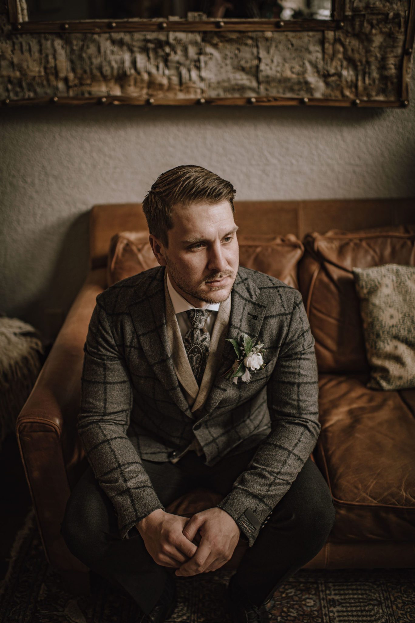 Styled groom poses in a three piece grey plaid suit from Ed Williams Mens Wear