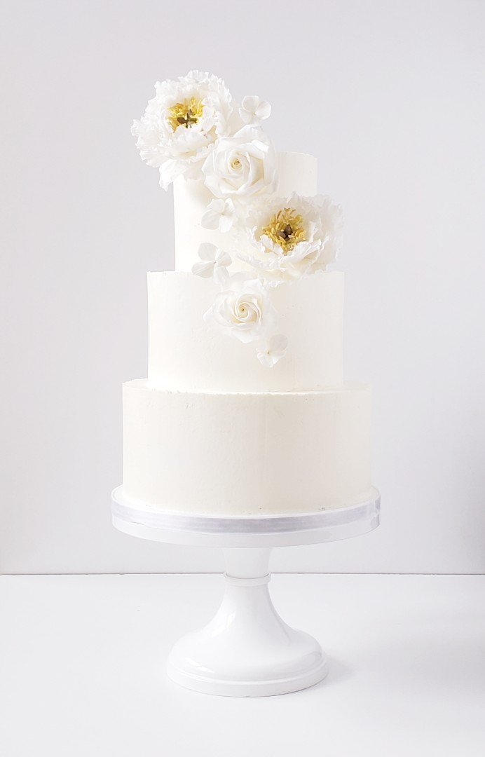 White and yellow handmade sugar flowers adorn a stunning monochromatic wedding cake