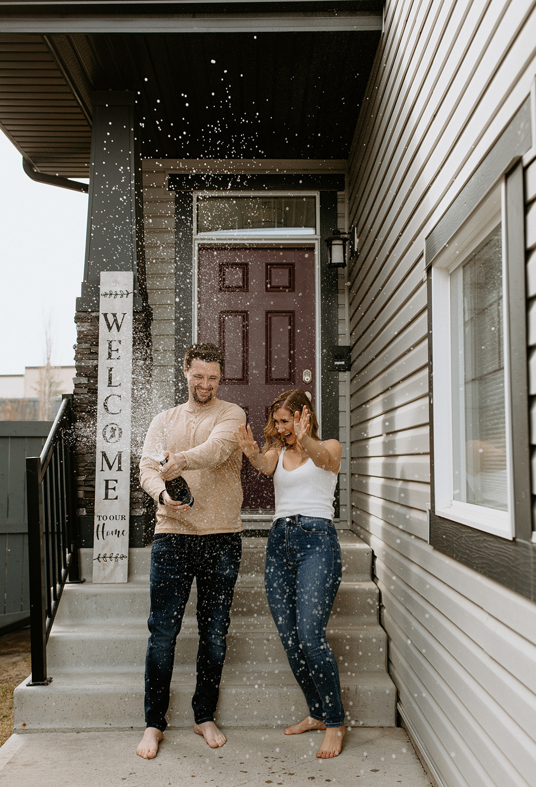 Couple pops champagne on the steps of their new home