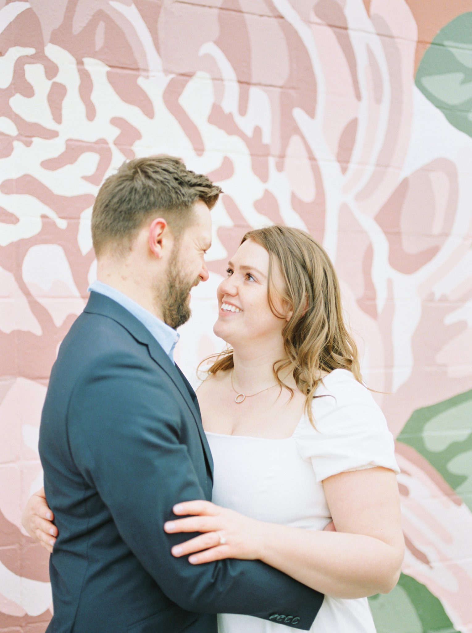 Stylish engagement photos in front of a pink floral mural in Edmonton Alberta at Manchester Square