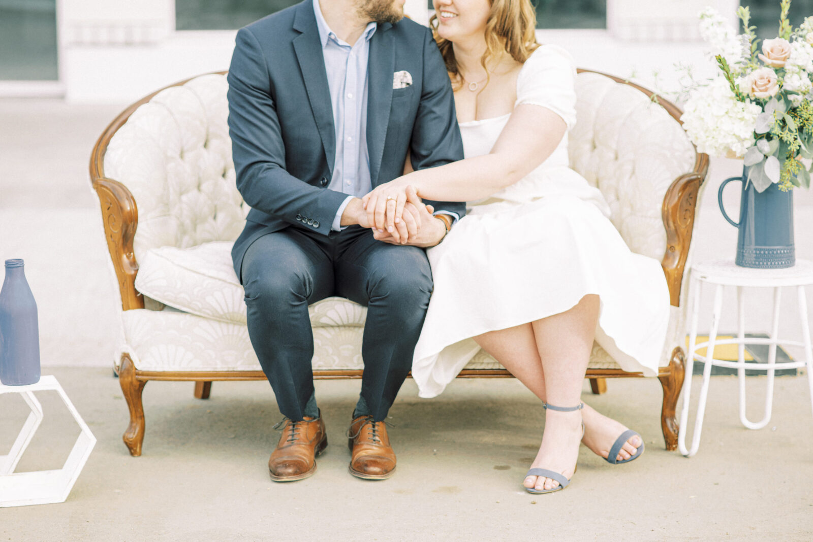 Romantic and playful engagement session filled with engagement session prop inspiration including a white love seat and spring-inspired bouquet