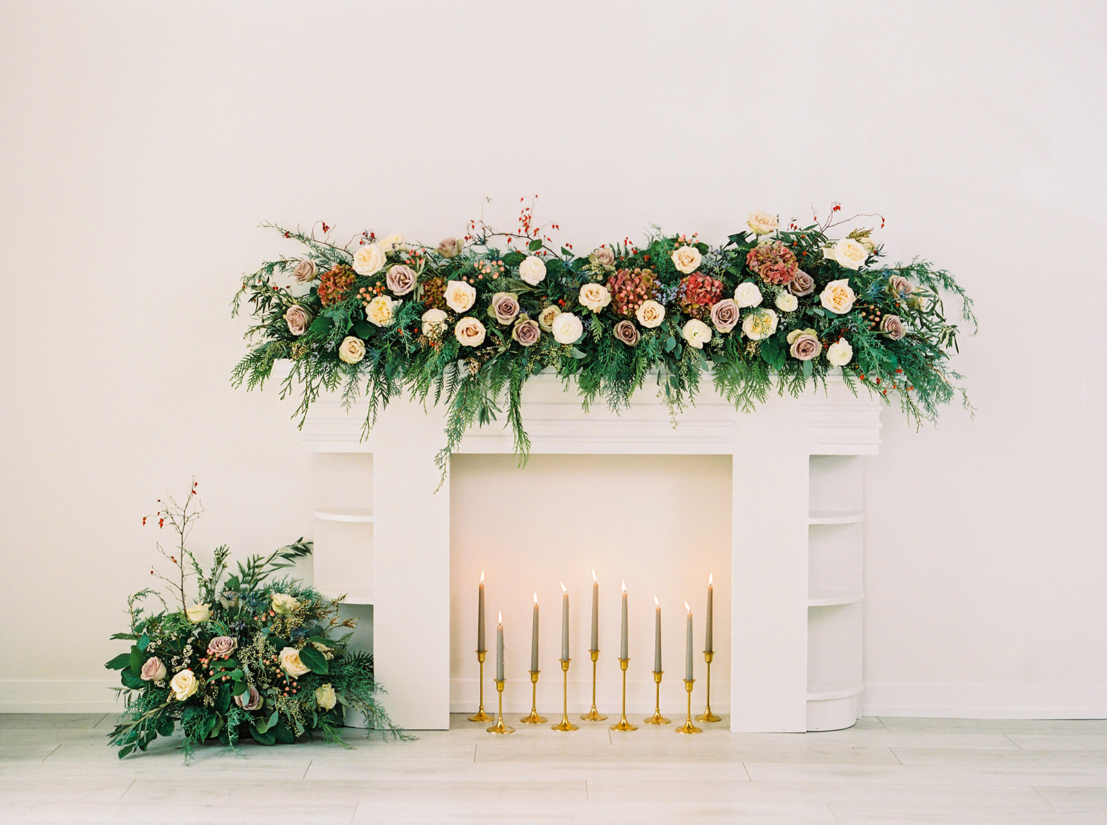White faux fireplace adorned with winter blooms and greenery