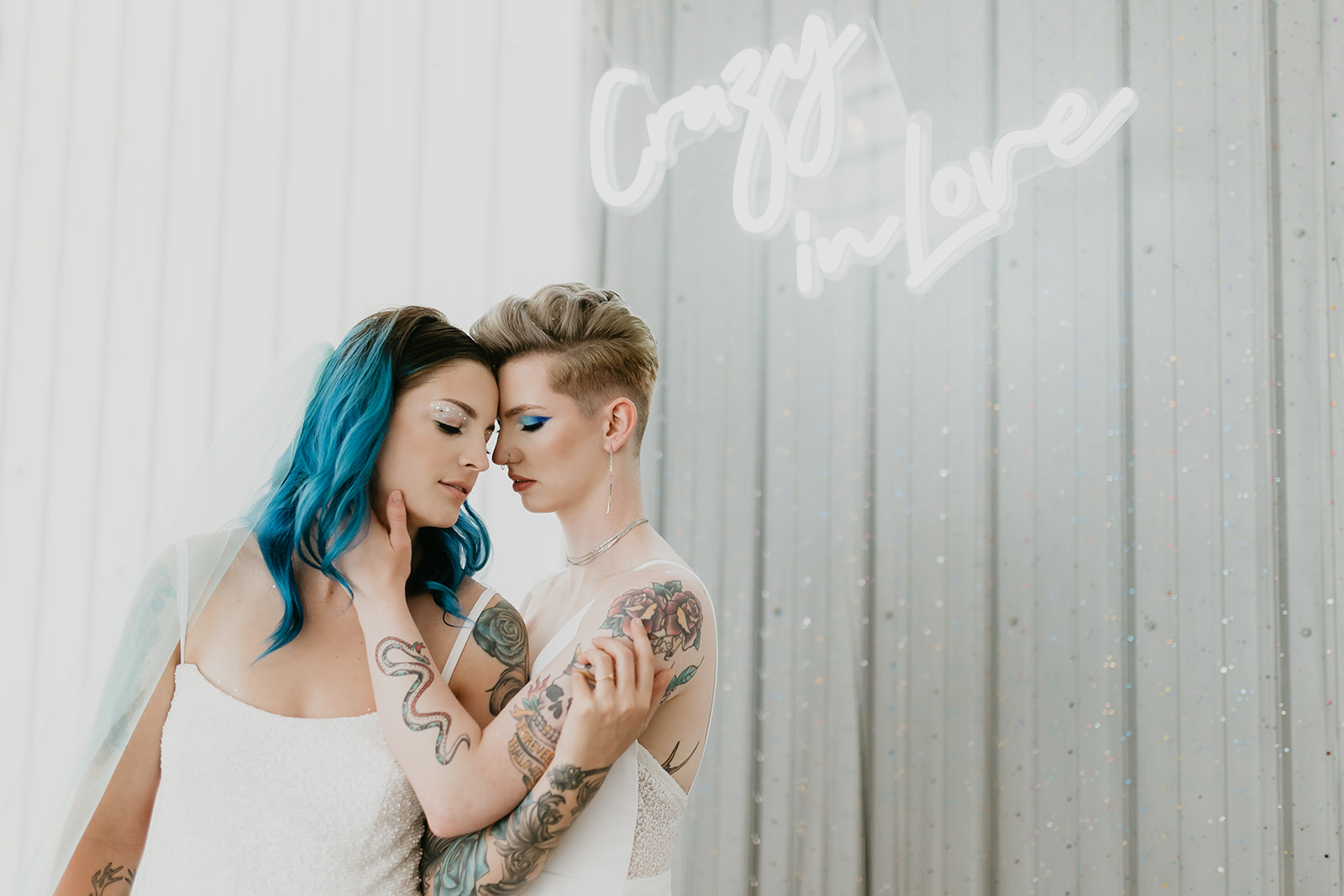 Rocker styled brides pose in front of a Crazy in Love neon sign