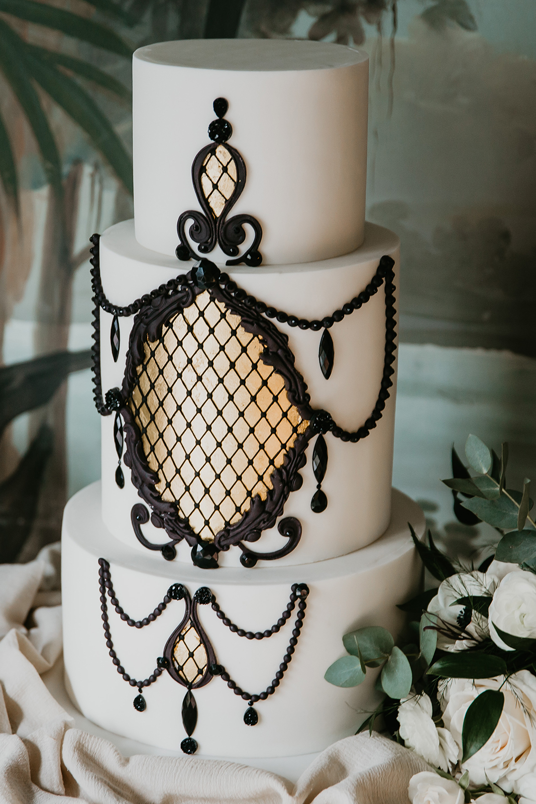 Three tiered white Great Gatsby inspired wedding cake with gold and black details