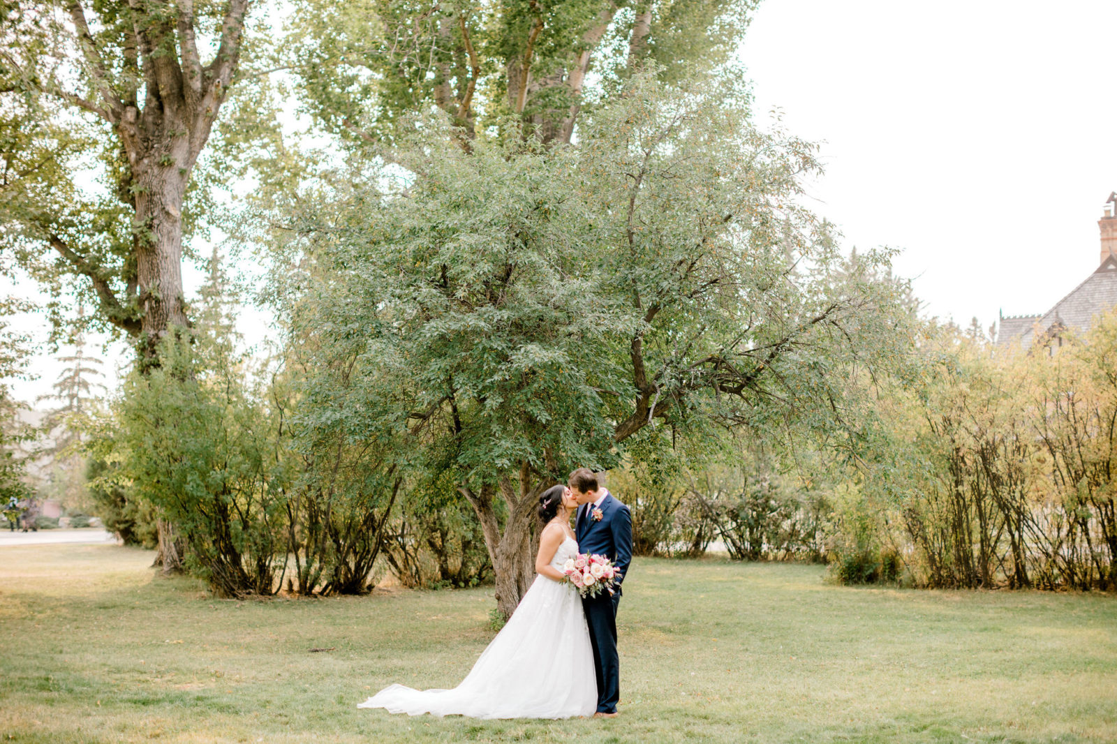 Stunning and romantic bride and groom share a kiss on their wedding day in a Calgary Alberta park