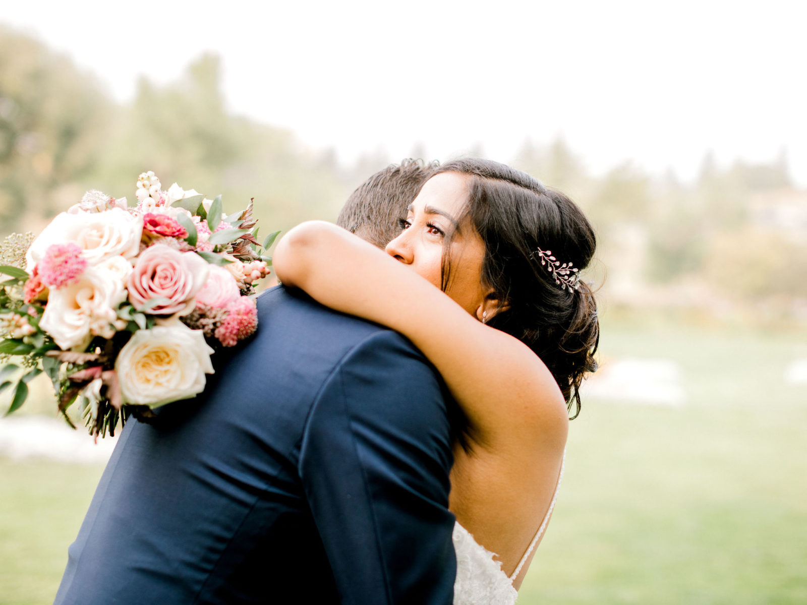 Bride hugs her groom after theiy share their wedding day first look