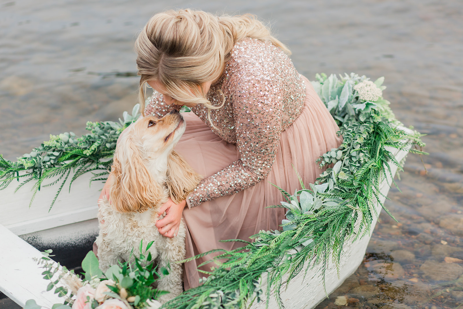 Eloping bride and her Spaniel in a white rowboat decorated with greenery