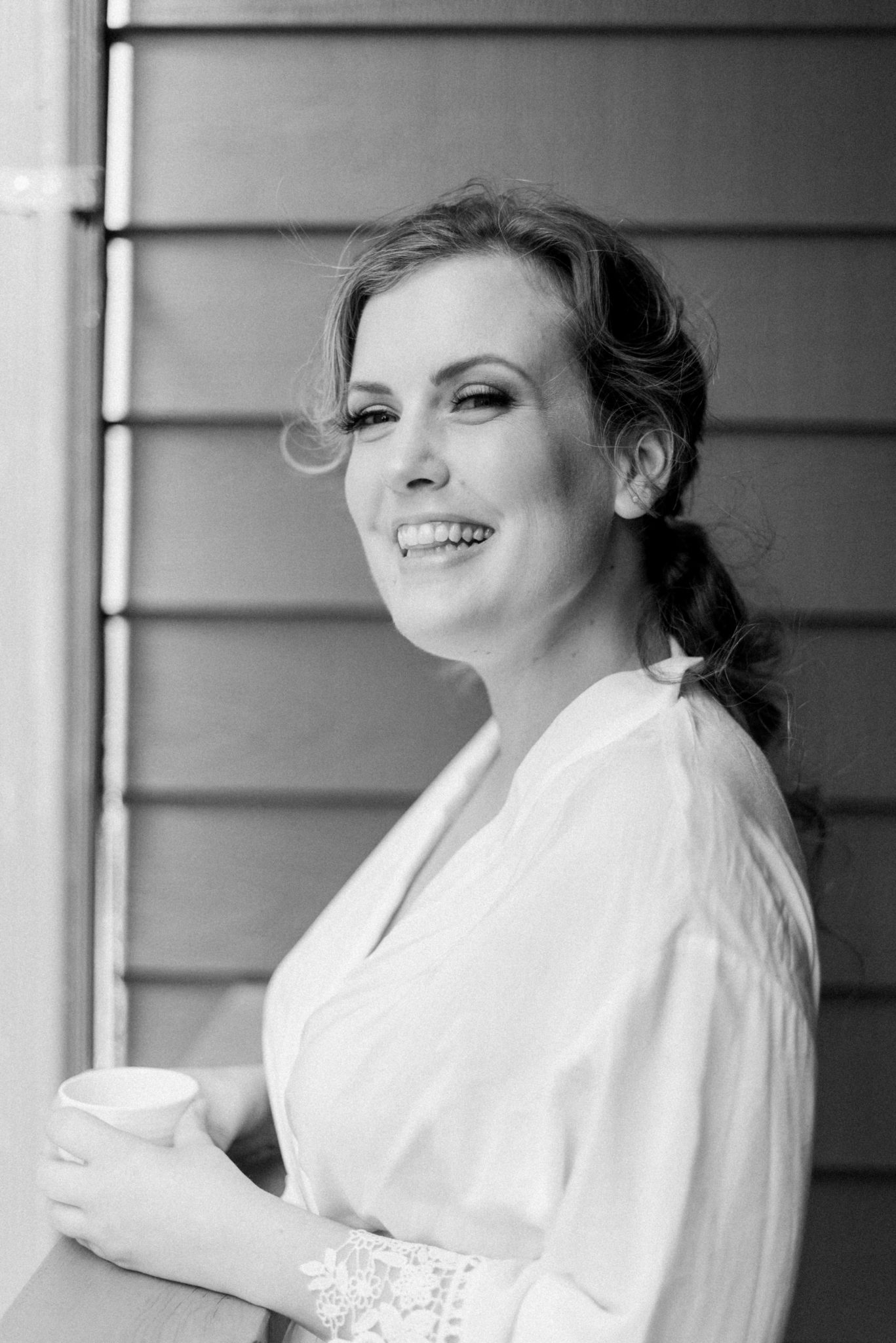 Bride drinks coffee on the balcony of the Fairmont Jasper Park Lodge on the morning of her intimate mountain elopement