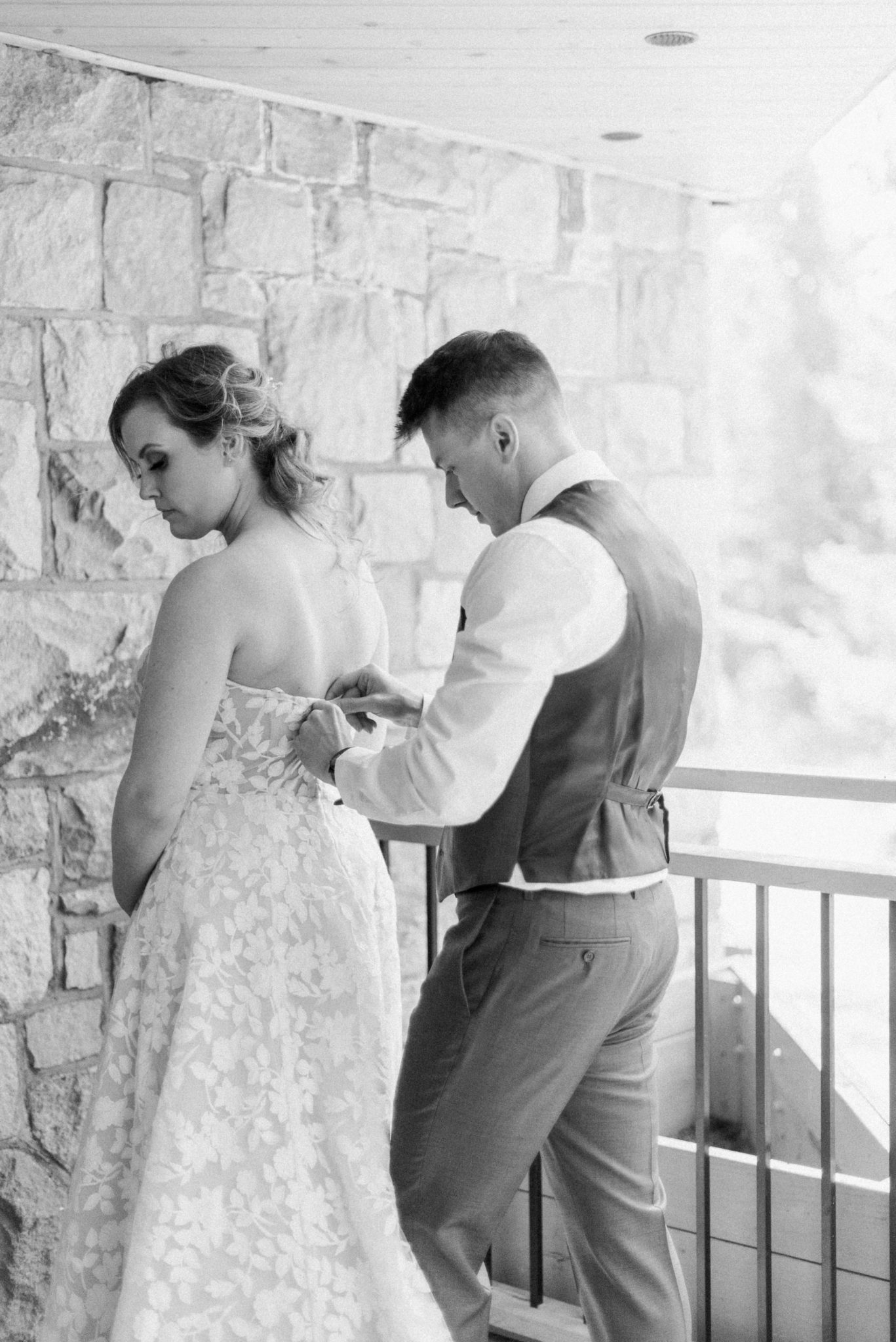 Groom helps his bride into her wedding dress on the morning of their intimate mountain elopement at the Fairmont Jasper Park Lodge