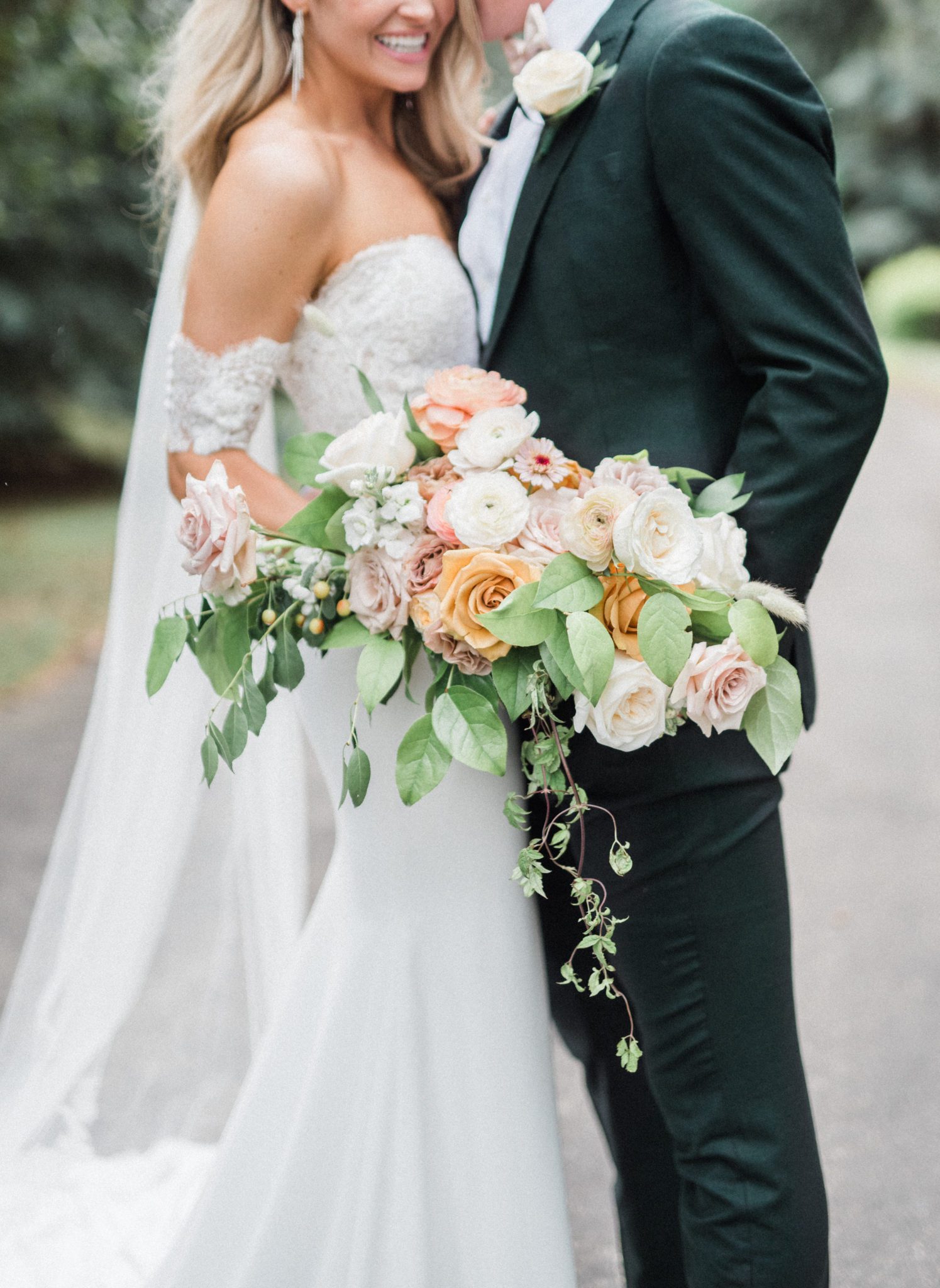 Classically styled bride and groom pose with a romantic bridal bouquet