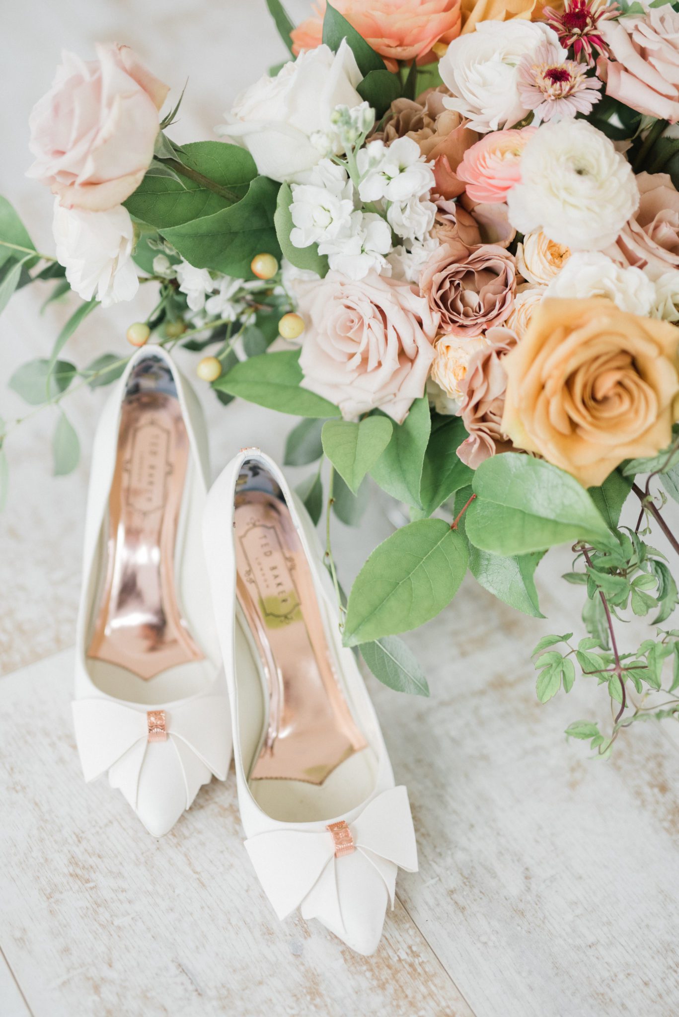 White bridal high heels with rose gold accents and bridal bouquet